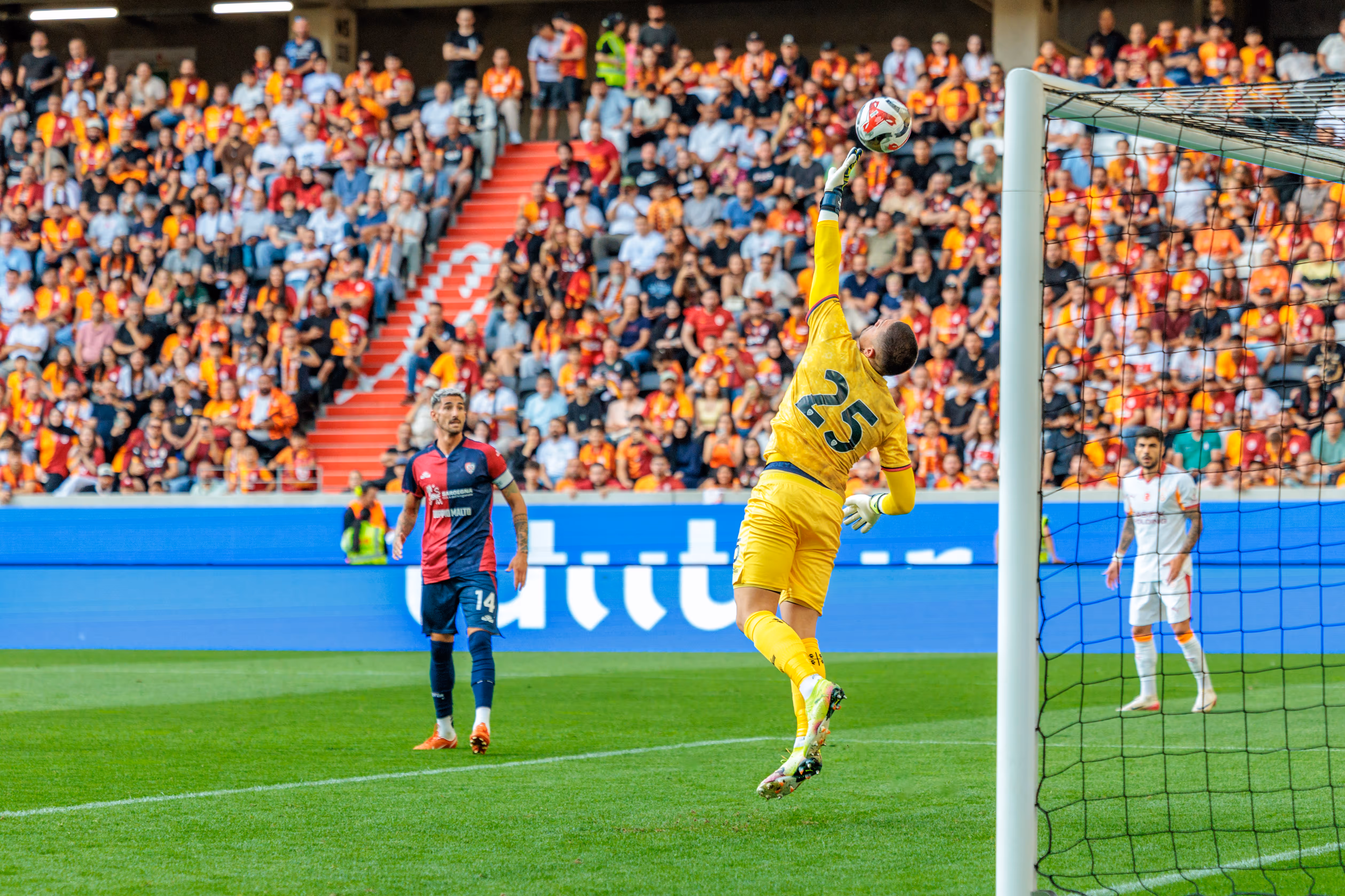 Ein Fußballtorwart in gelbem Trikot springt in der Raiffeisen Arena nach dem Ball, um einen Torschuss während der Nero Summer Series abzuwehren - 2025/07/23