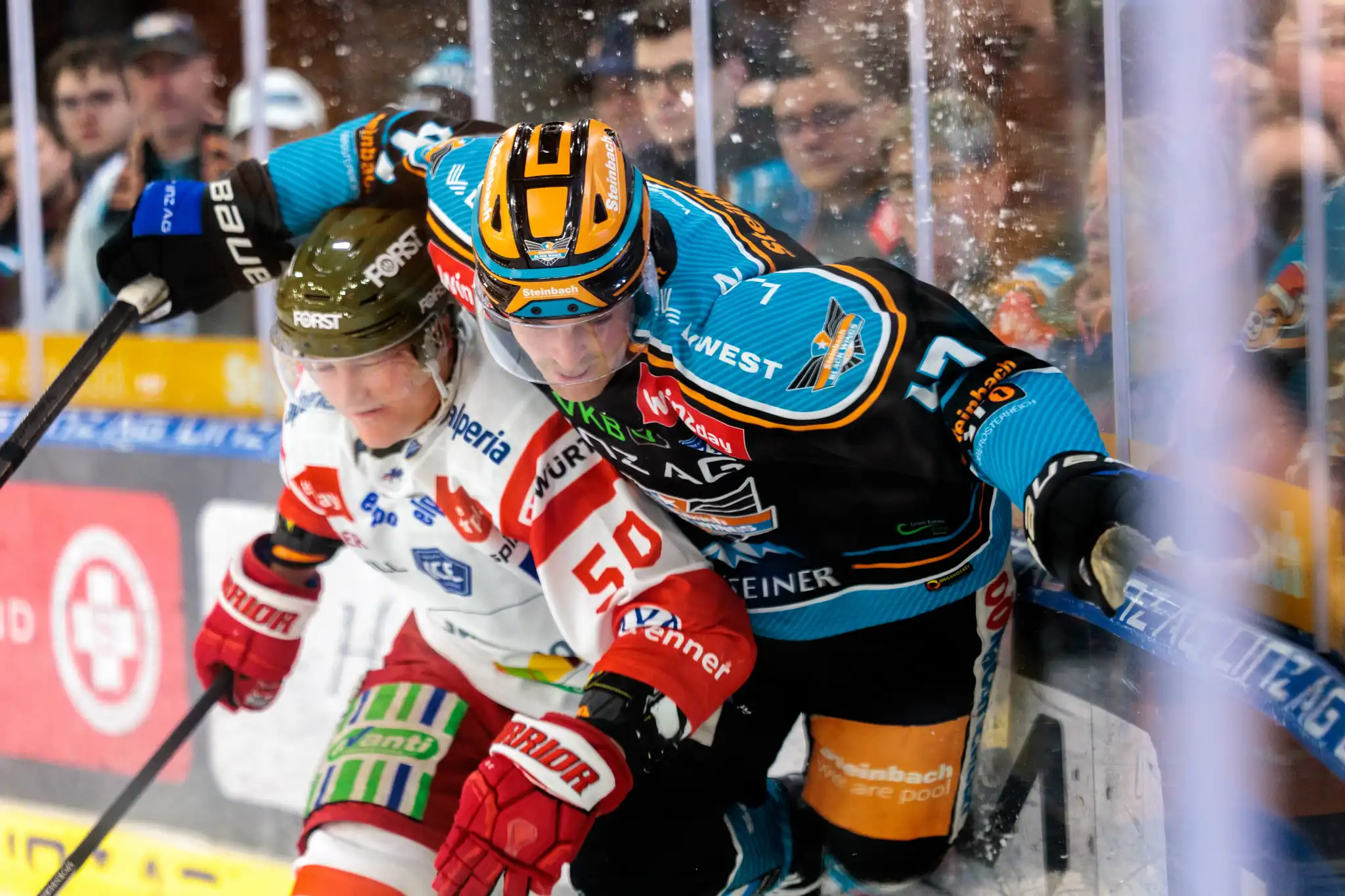 Nahaufnahme zweier Eishockeyspieler im intensiven Zweikampf an der Eisbande der Linzer Eisarena