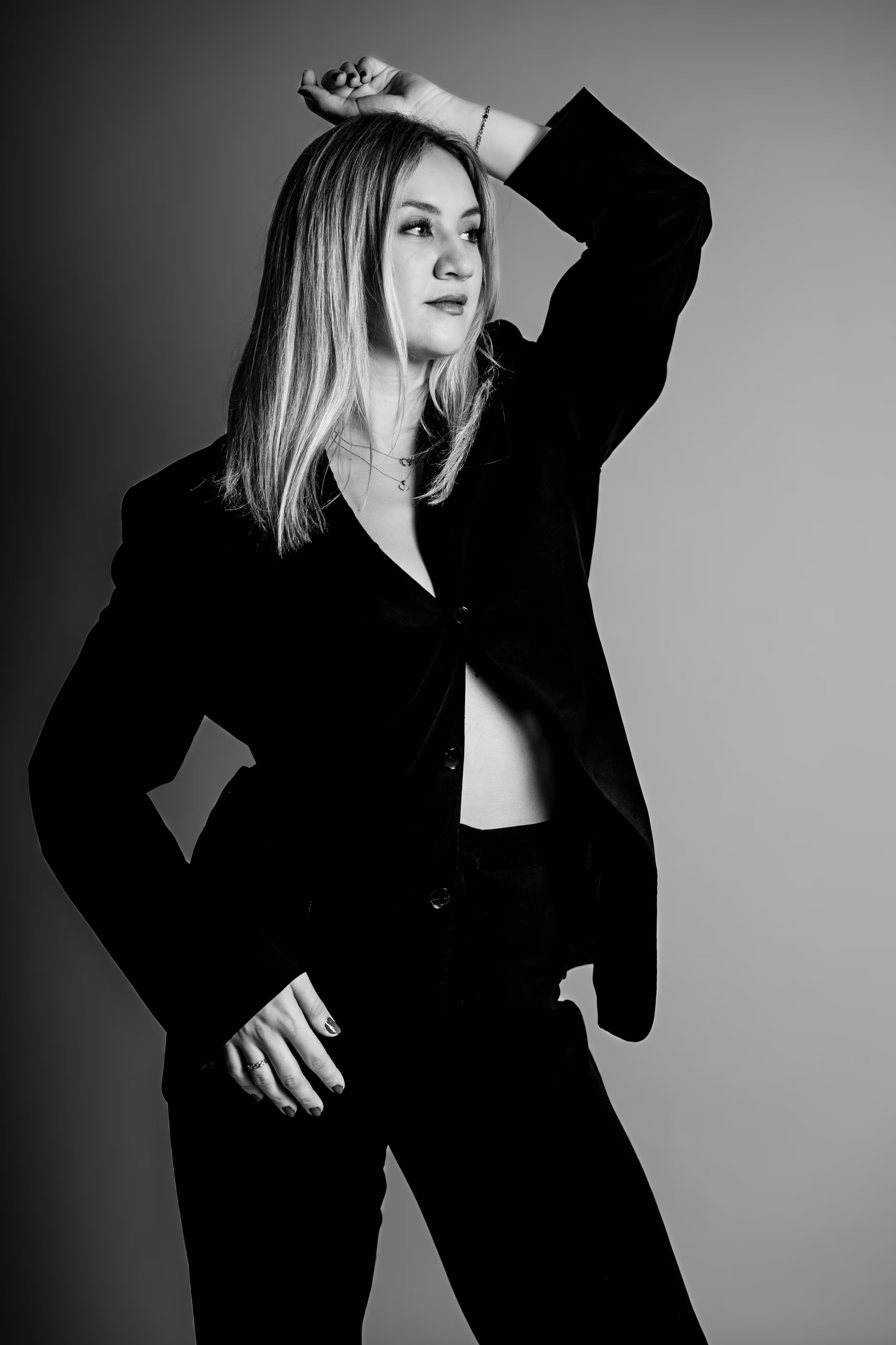 Elegante Schwarz-Weiß-Aufnahme von Model Anna, die im Studio in einem schwarzen Hosenanzug eine selbstbewusste Business-Pose einnimmt