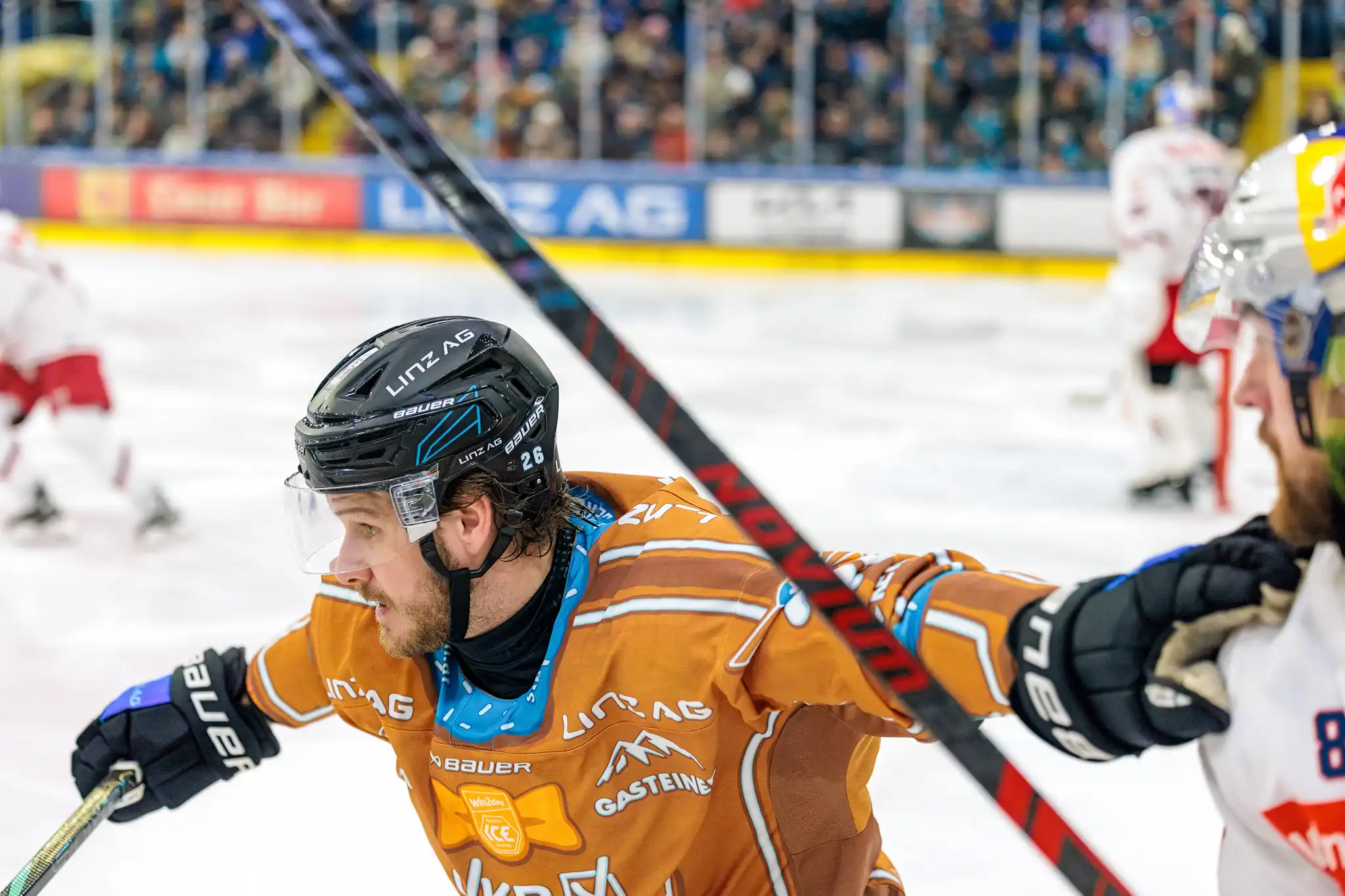 Der Eishockeyspieler Barron der Black Wings Linz mit der Nummer 26 im orangefarbenen Trikot während eines Spiels auf dem Eis