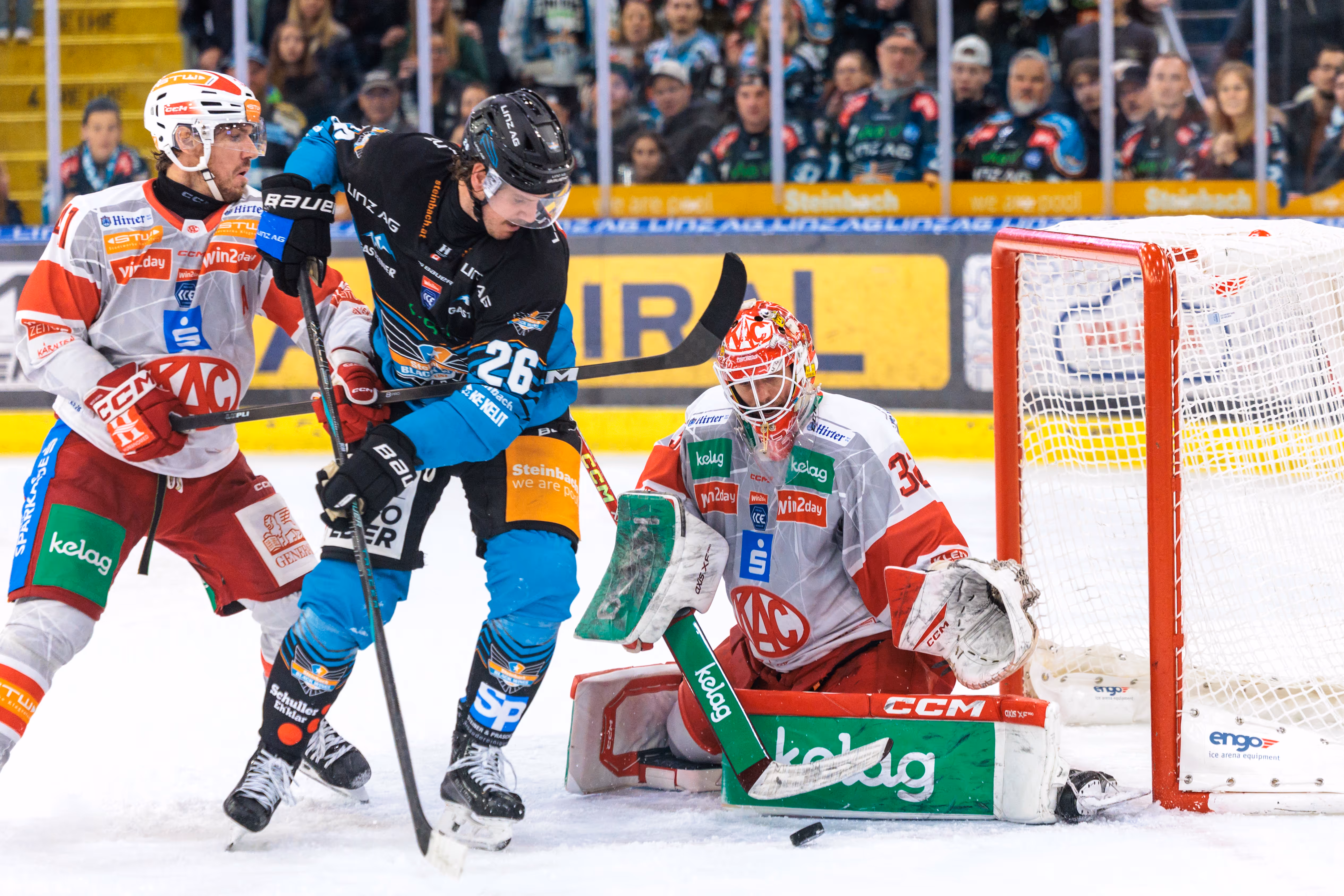 Der Stürmer der Steinbach Black Wings, Travis Barron, versucht in einer intensiven Spielszene den Puck am KAC-Goalie Sebastian Dahm vorbei ins Tor zu schießen