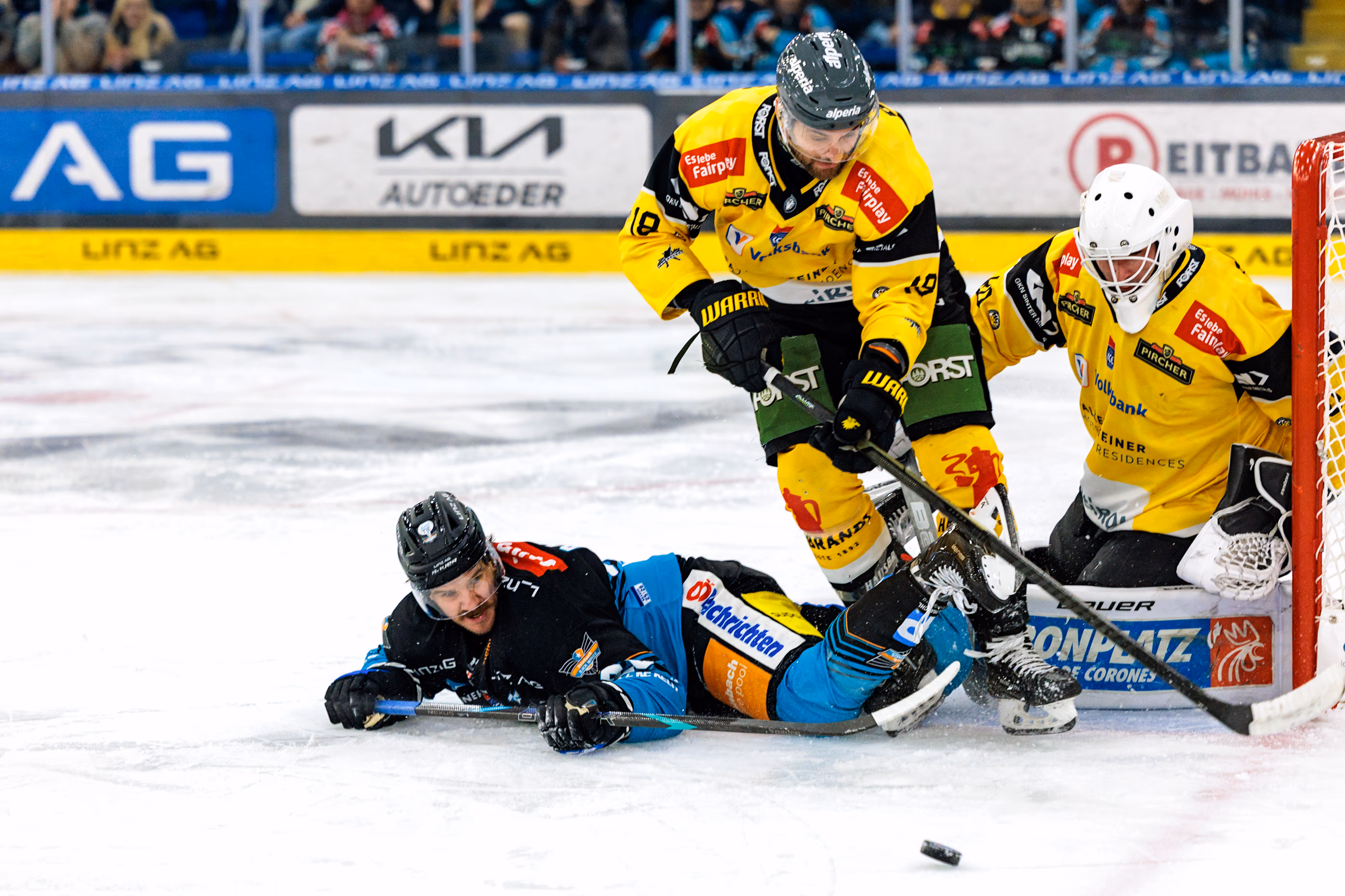 Intensive Spielszene beim Eishockey, bei der der Linzer Stürmer Travis Barron nach einem Zweikampf vor dem Tor des HC Pustertal zu Fall kommt