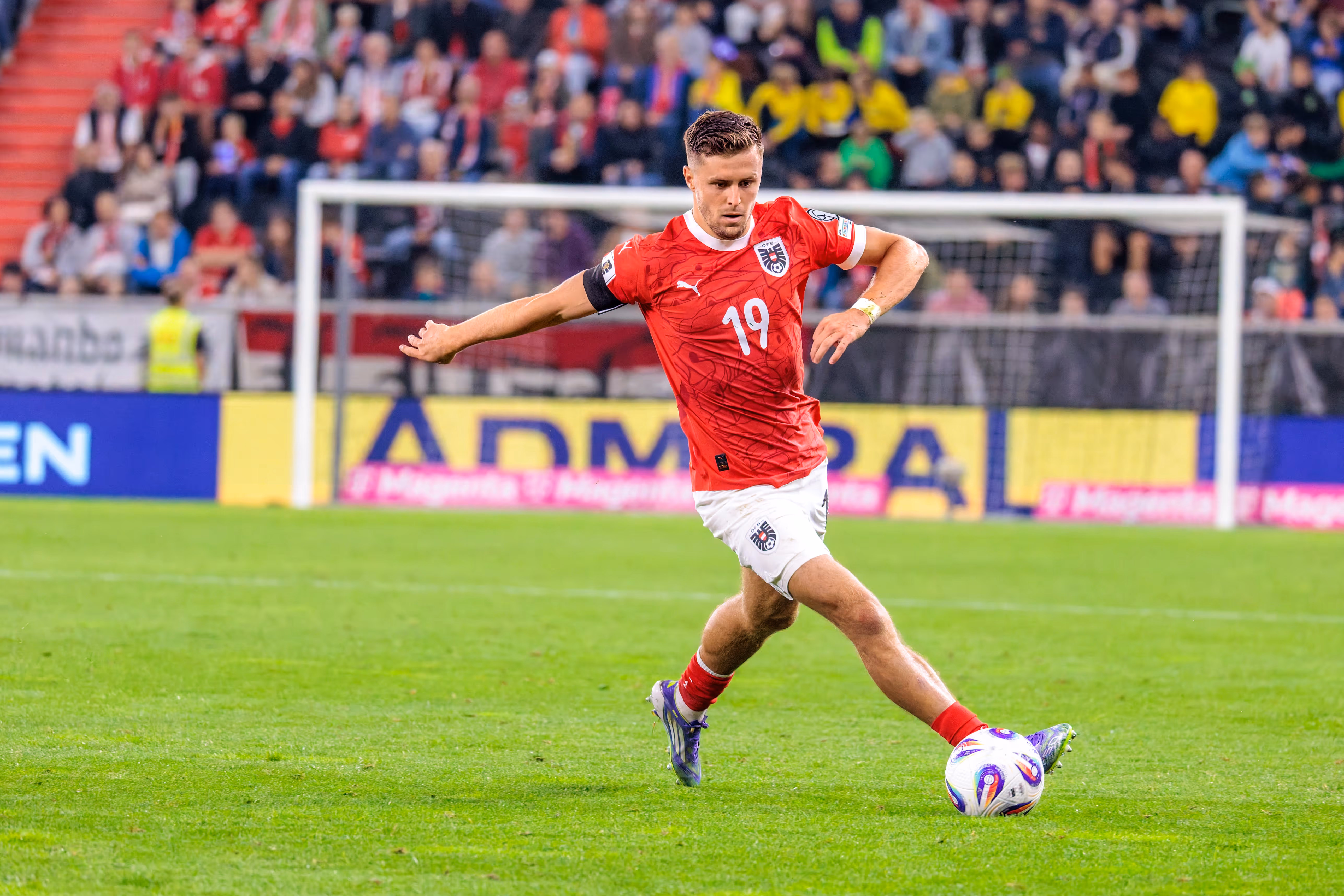 Der österreichische Nationalspieler Christoph Baumgartner kontrolliert den Ball im roten Trikot mit der Nummer 19 während eines Fußballspiels