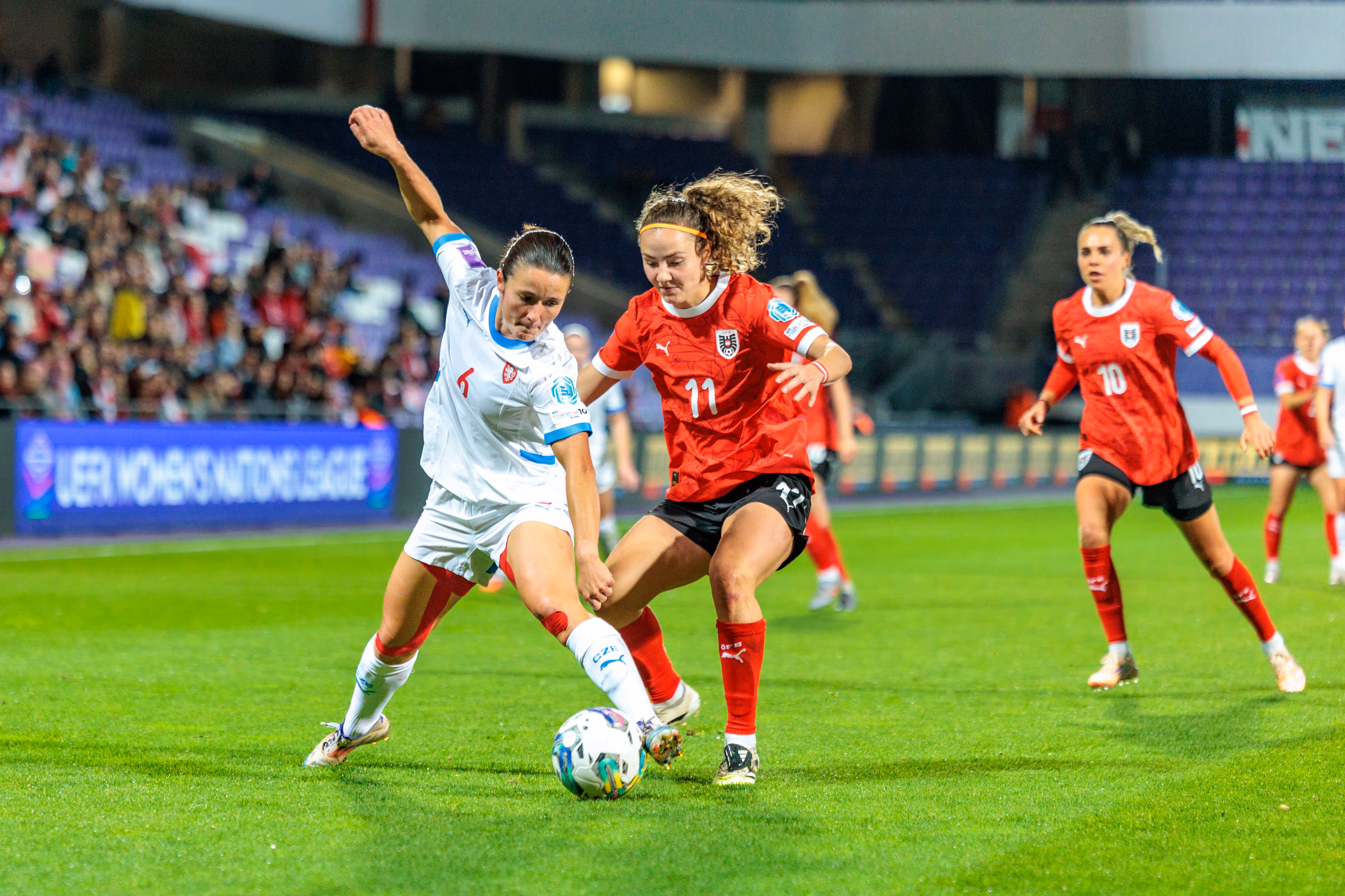 Österreichs Stürmerin Eileen Campbell im roten Trikot wird während ihres Angriffs von einer tschechischen Gegenspielerin im Zweikampf attackiert