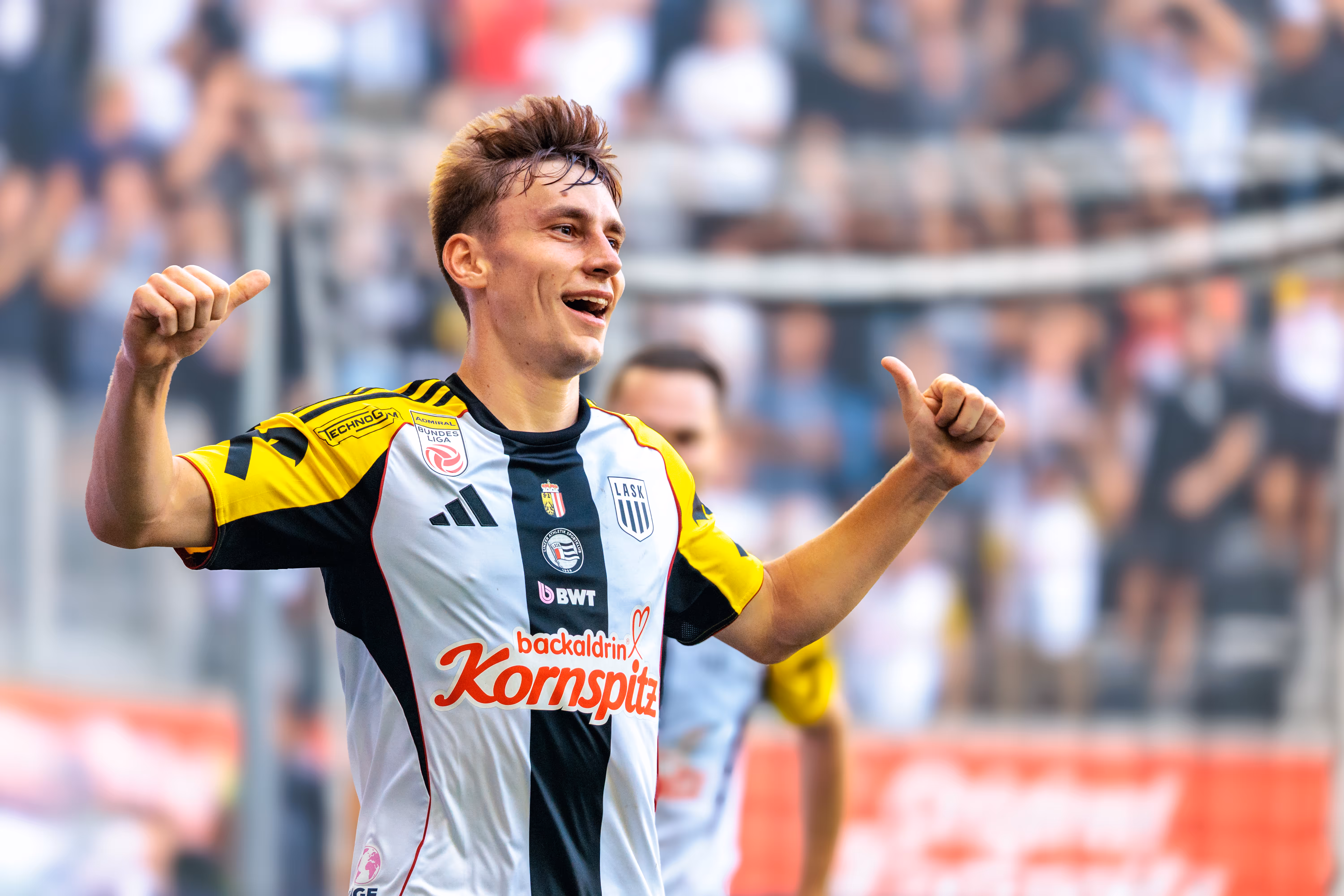 Der überglückliche LASK-Spieler Christoph Lang feiert seinen Treffer mit einem breiten Lächeln und streckt beide Daumen jubelnd in die Höhe
