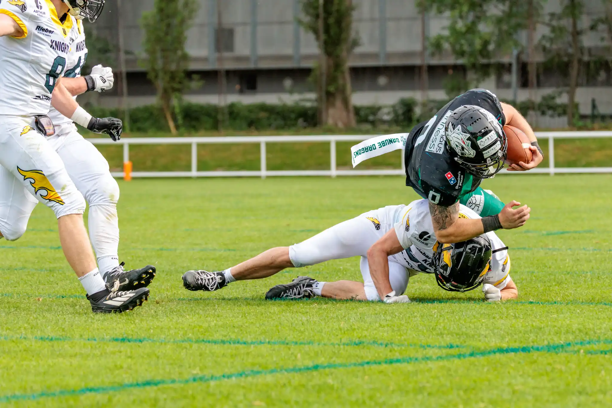 Ein Spieler der Danube Dragons wird von einem Vienna Knights Verteidiger am Boden getackelt während eines intensiven American Football Spiels in der Austrian Football League