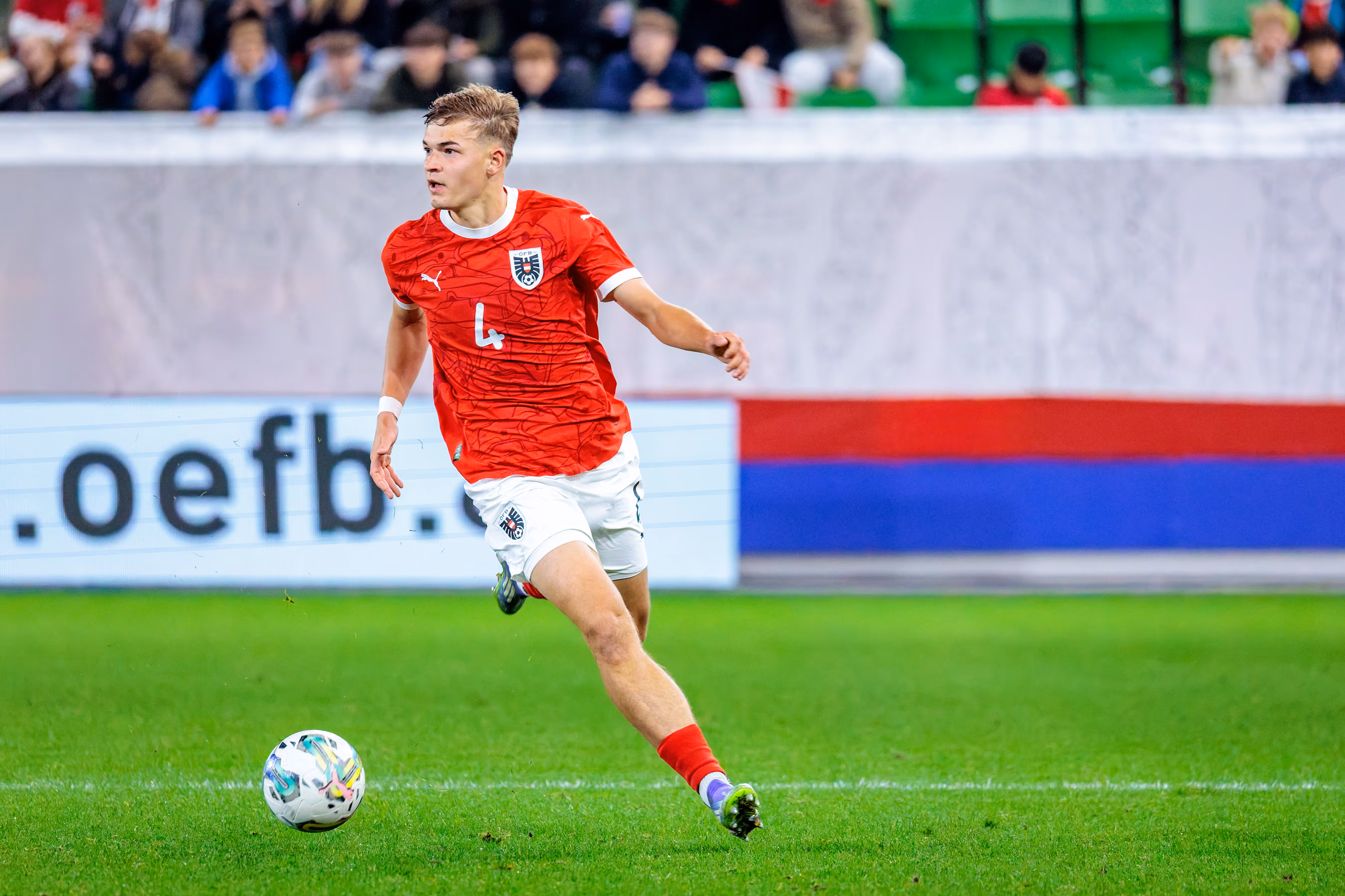 Der österreichische U21-Nationalspieler David Piczka dribbelt im roten Trikot mit der Nummer 4 dynamisch mit dem Ball am Fuß