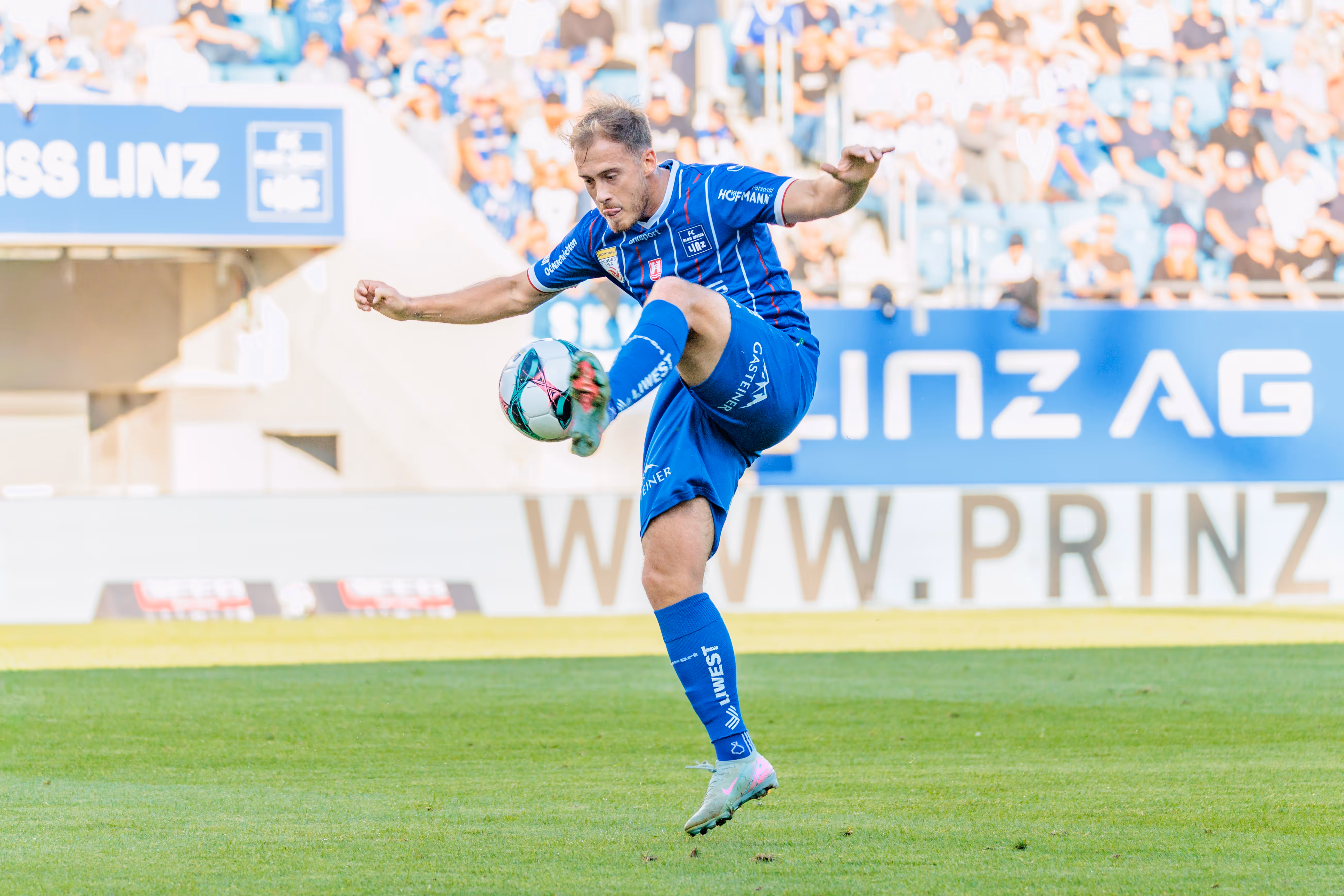 Fußballspieler Dominik Reiter nimmt in seinem blauen Trikot einen Fußball in der Luft an