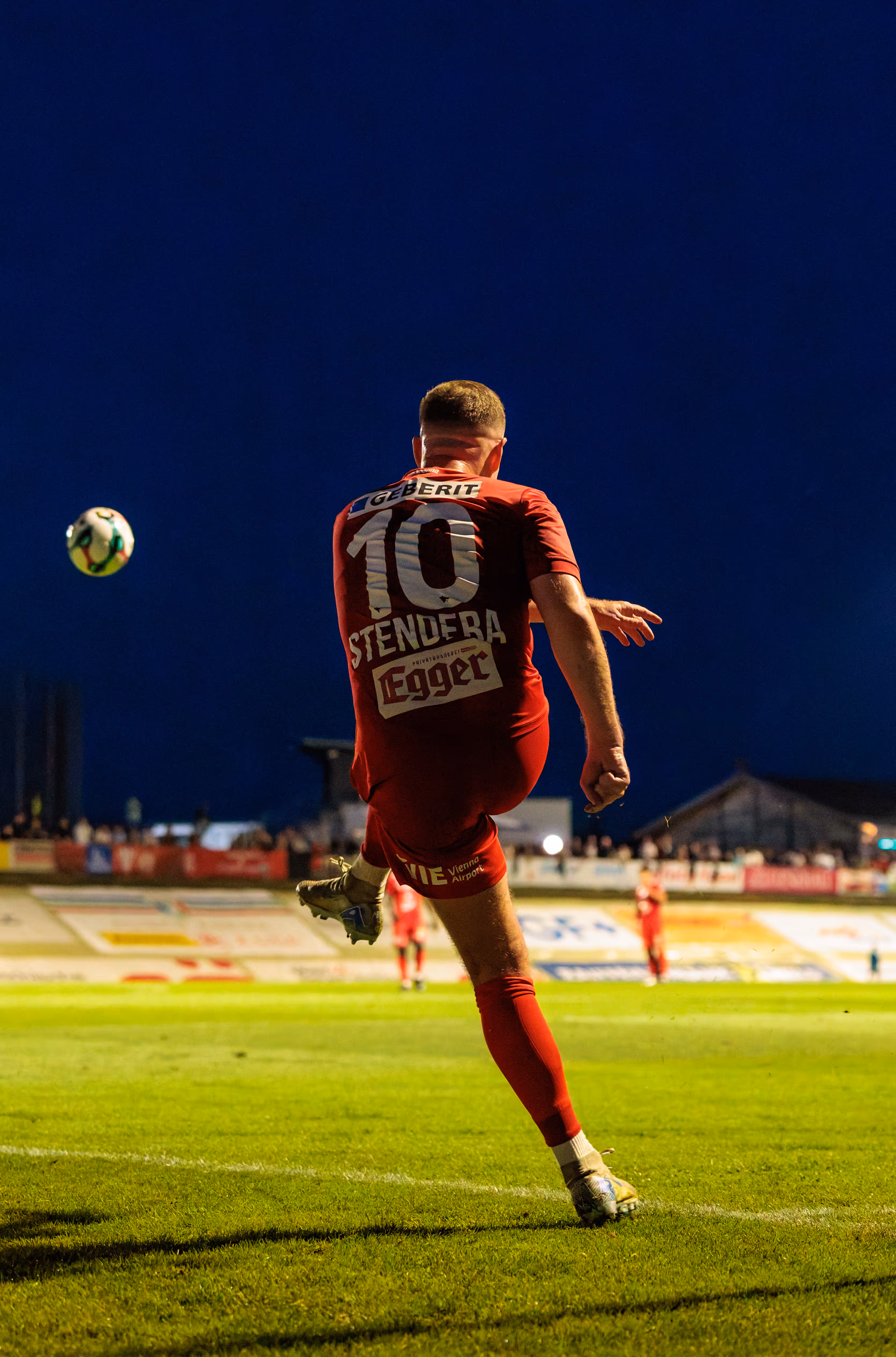 Ein Spieler des SKN St. Pölten mit der Rückennummer 10 schlägt im ÖFB-Cup einen Eckball unter dem dunklen Abendhimmel, während der Fußball in der Luft schwebt