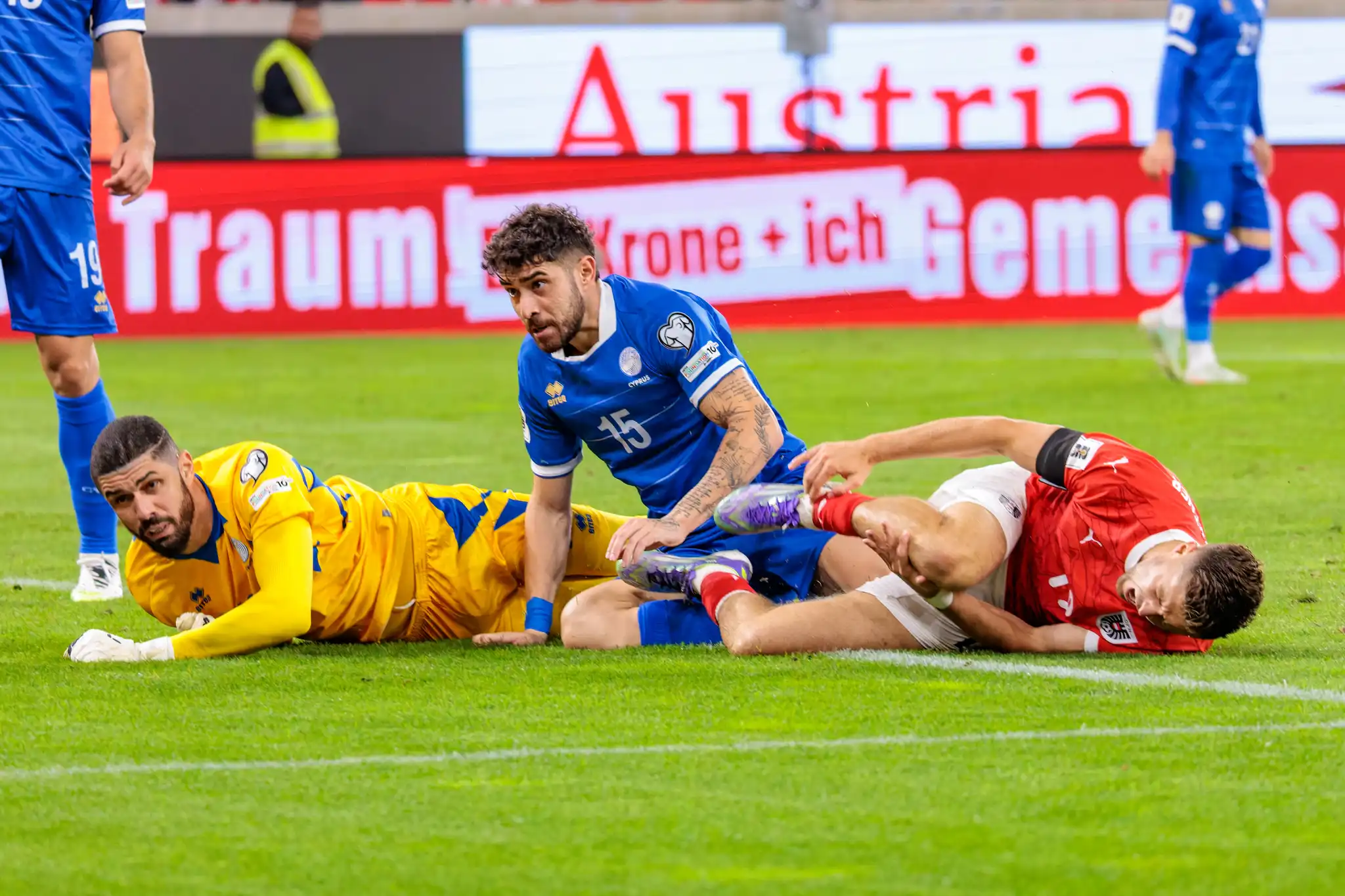 Der österreichische Spieler Christoph Baumgartner liegt nach einem Foul am Boden, mit dem zypriotischen Spieler Christos Shelis und Torwart Fabiano in unmittelbarer Nähe