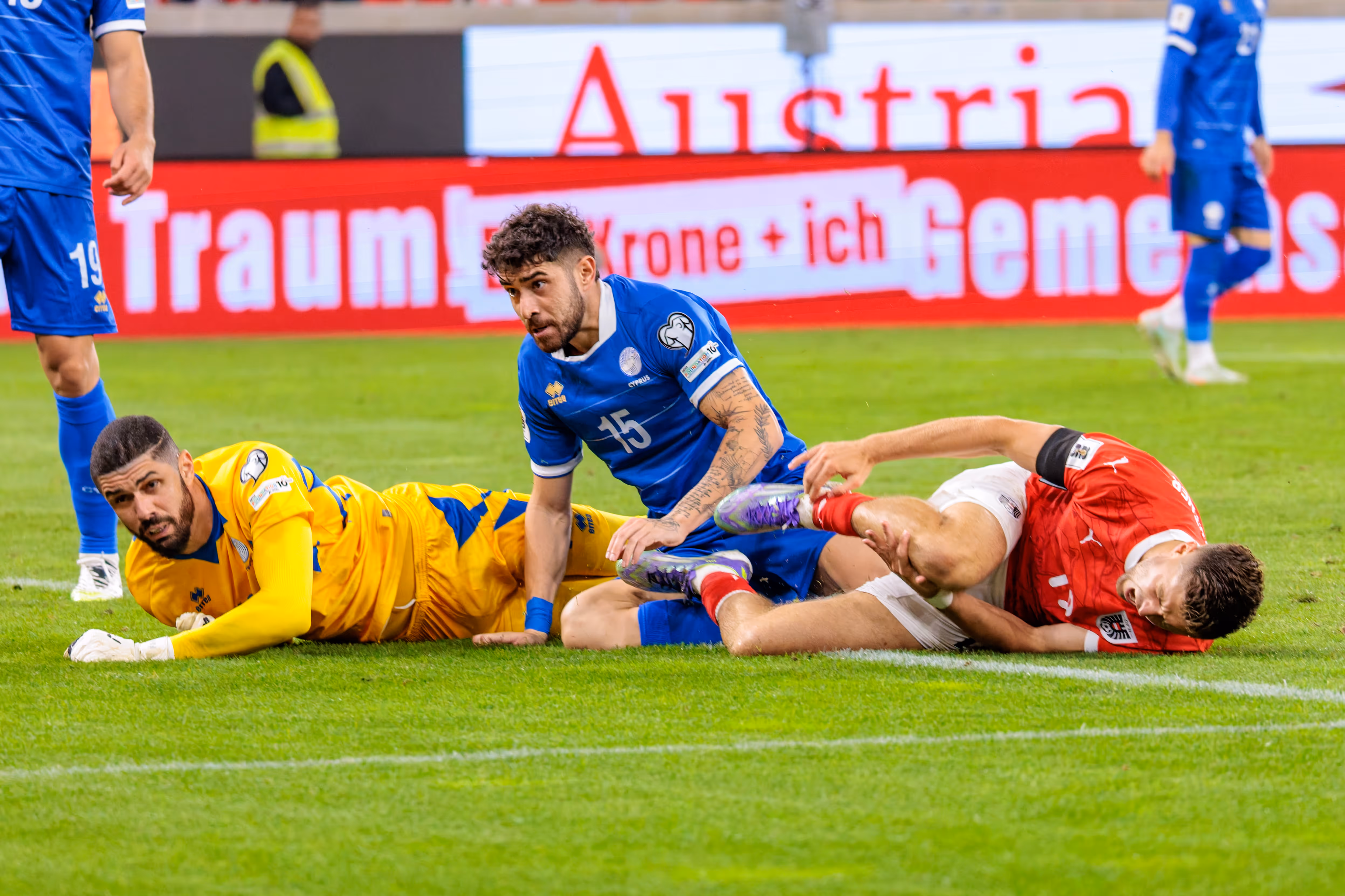 Der österreichische Spieler Christoph Baumgartner liegt nach einem Foul am Boden, mit dem zypriotischen Spieler Christos Shelis und Torwart Fabiano in unmittelbarer Nähe