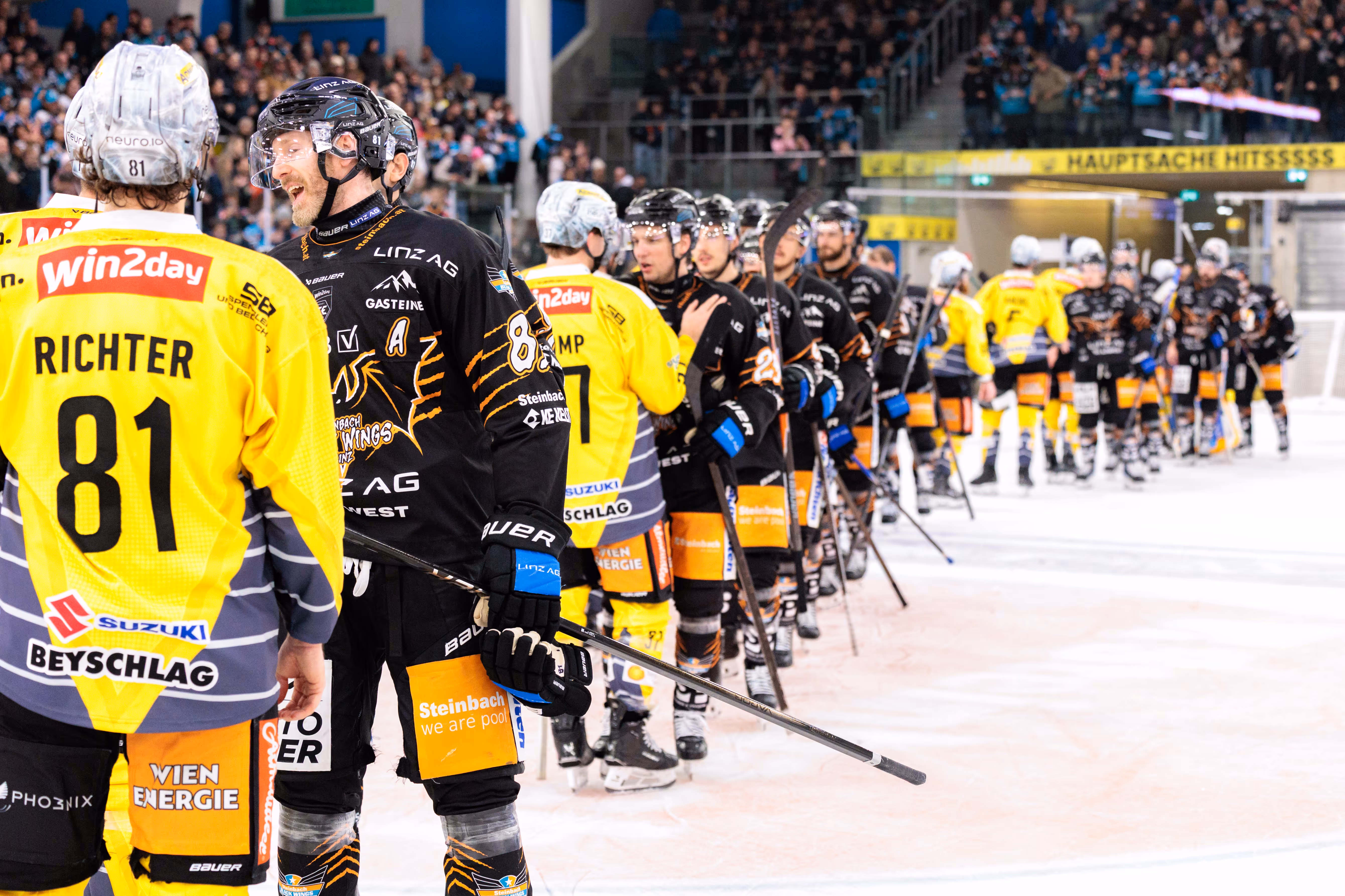 Eishockeyspieler Richter mit der Rückennummer 81 im gelben Trikot unterhält sich mit einem Spieler im schwarzen Trikot auf dem Eis nach einem Eishockeyspiel