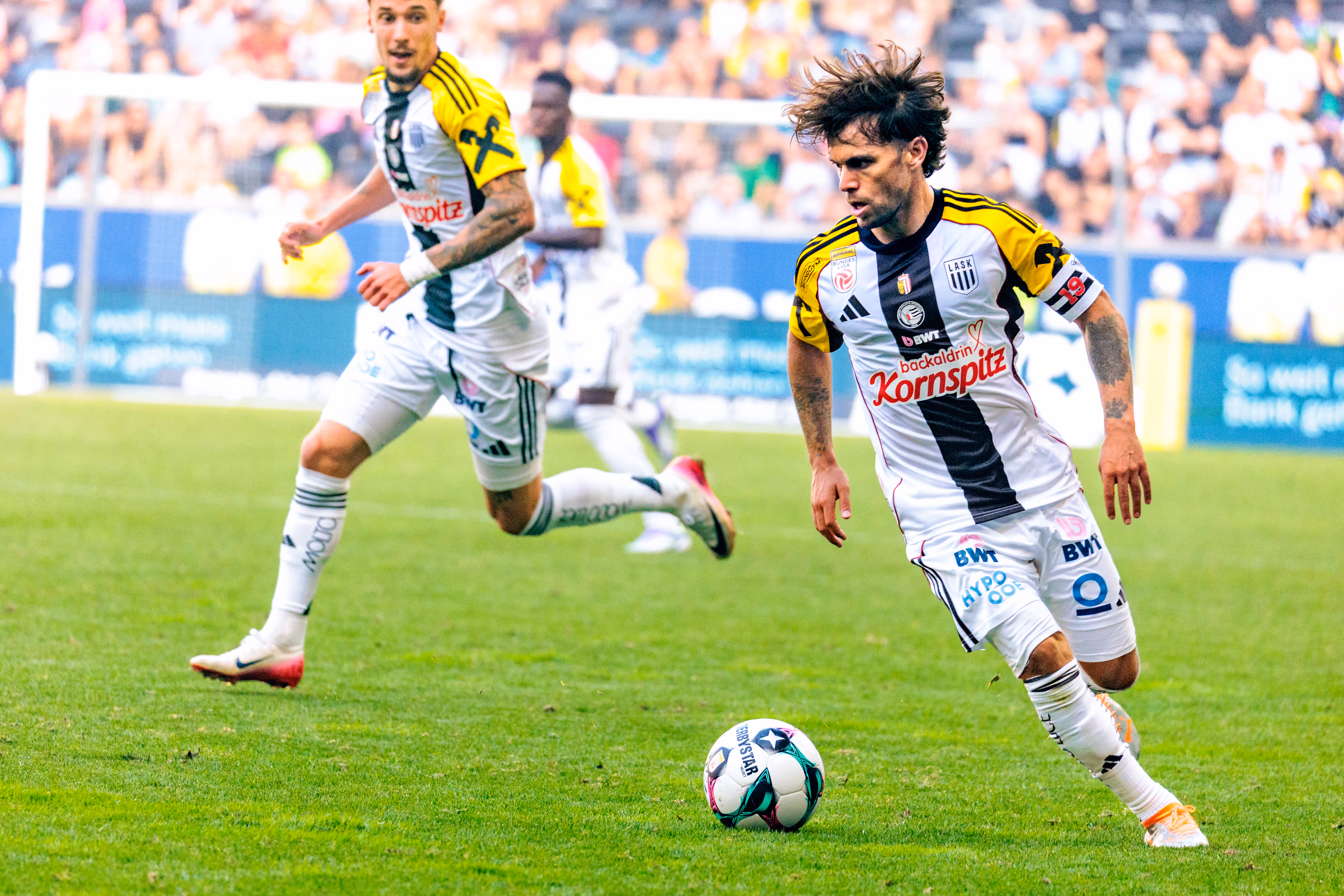 Der LASK-Kapitän Sascha Horvath treibt mit wilder Frisur und konzentriertem Blick den Ball nach vorne