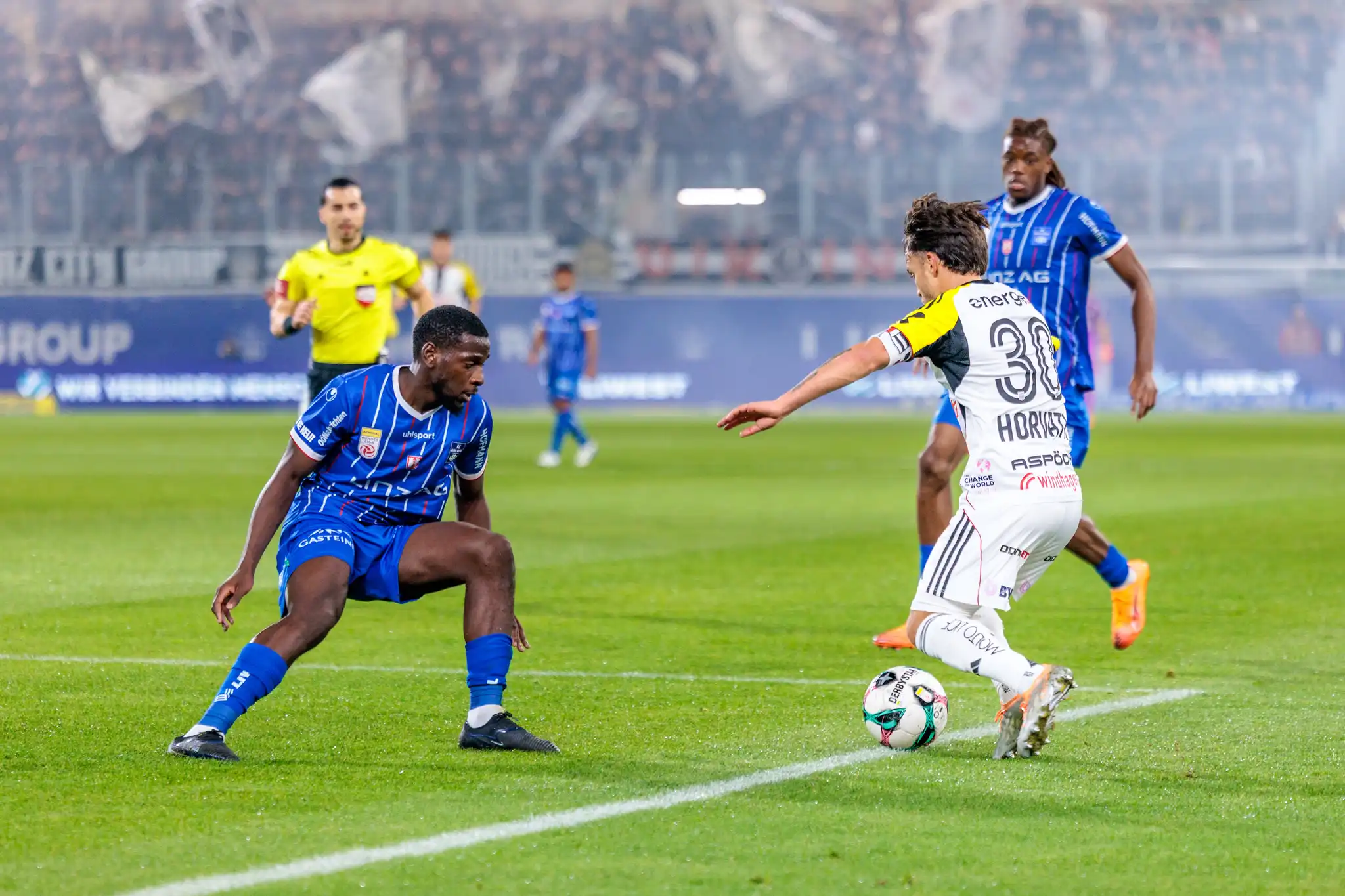 LASK-Kapitän Sascha Horvath dribbelt im intensiven Zweikampf gegen einen Verteidiger von Blau-Weiß Linz während des Linzer Derbys in der Fußball-Bundesliga