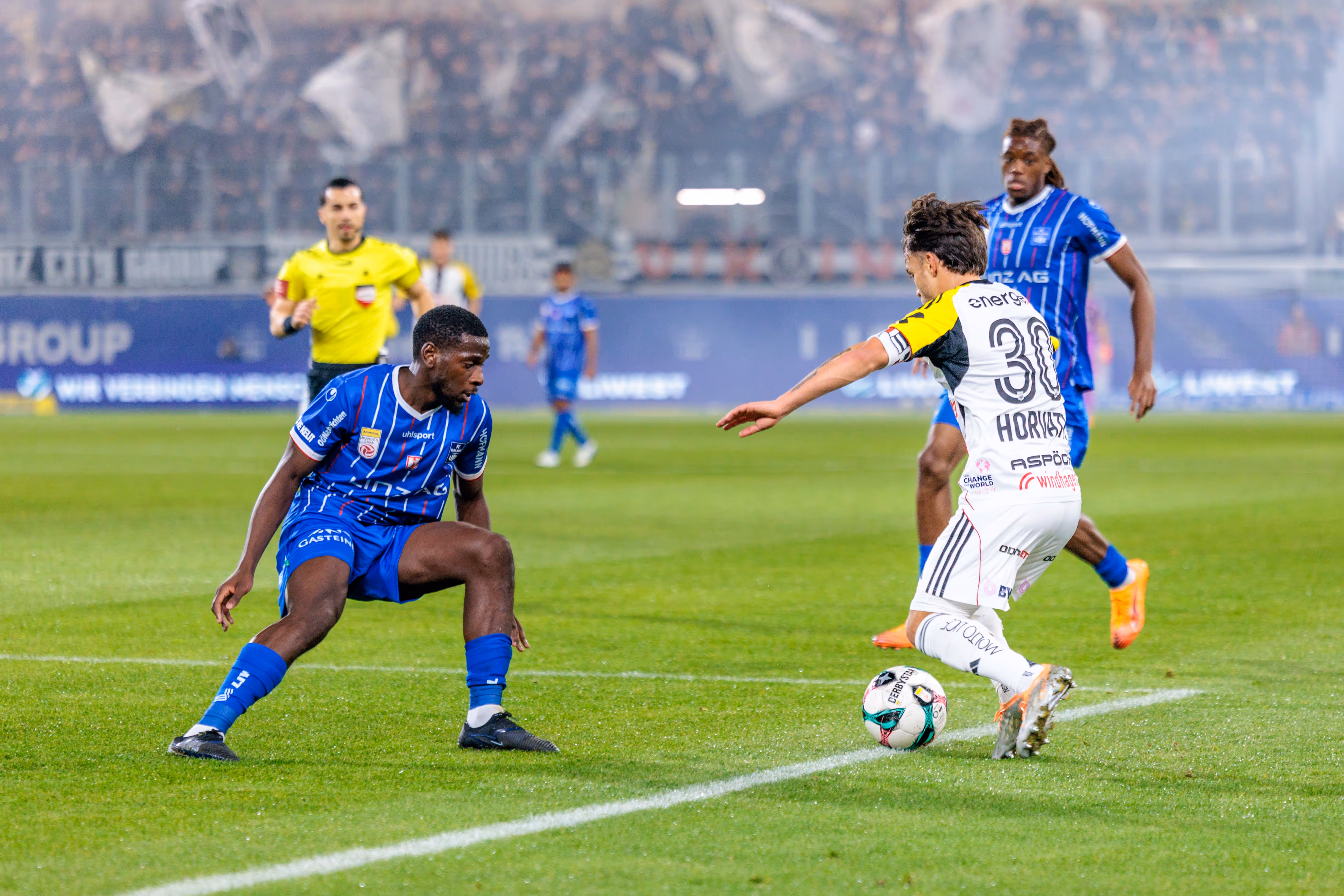 LASK-Kapitän Sascha Horvath dribbelt im intensiven Zweikampf gegen einen Verteidiger von Blau-Weiß Linz während des Linzer Derbys in der Fußball-Bundesliga