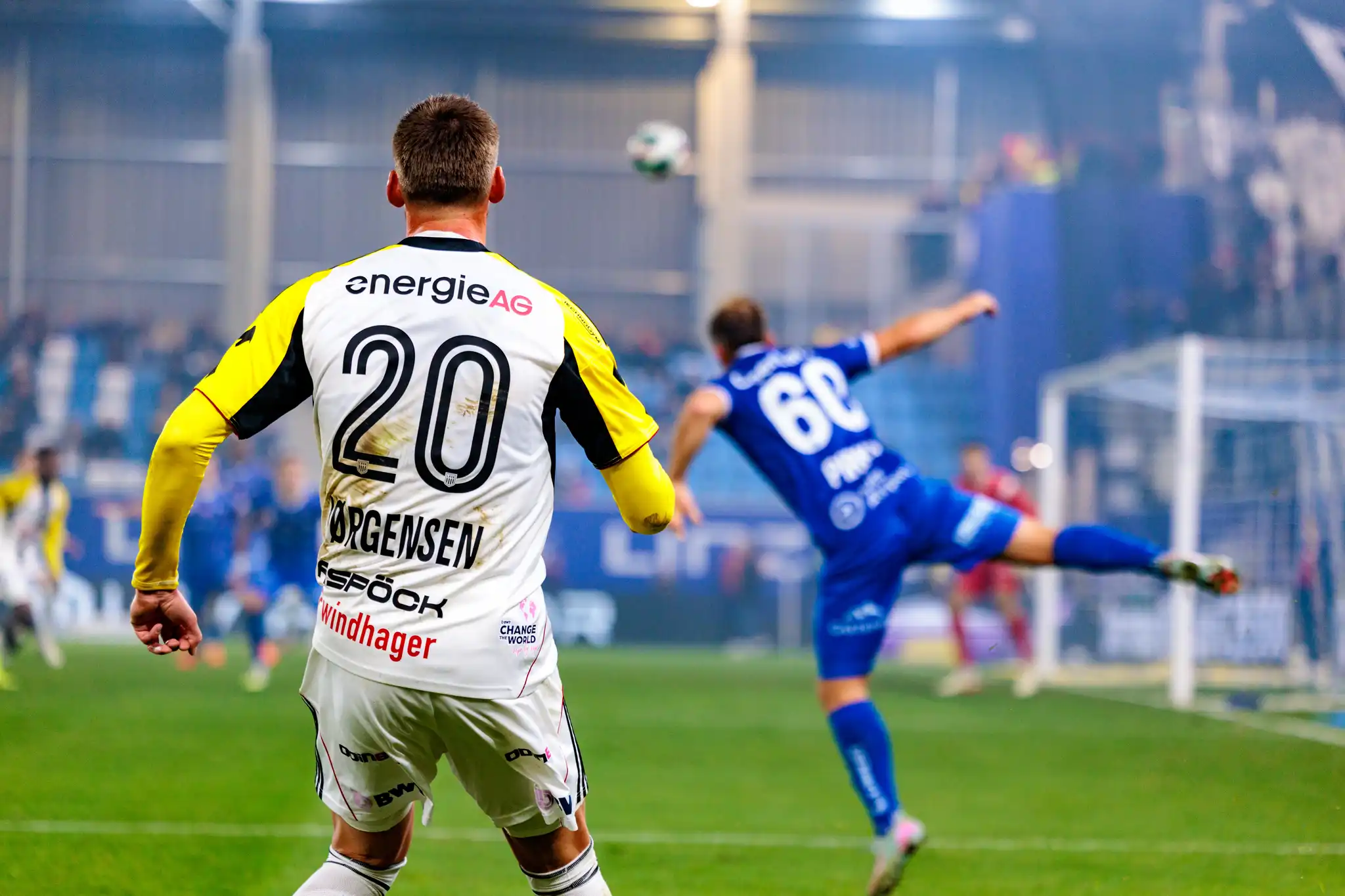 LASK-Spieler Elias Jørgensen mit der Rückennummer 20 beobachtet im Linzer Derby eine Spielszene, während ein Spieler von Blau-Weiß Linz den Ball klärt