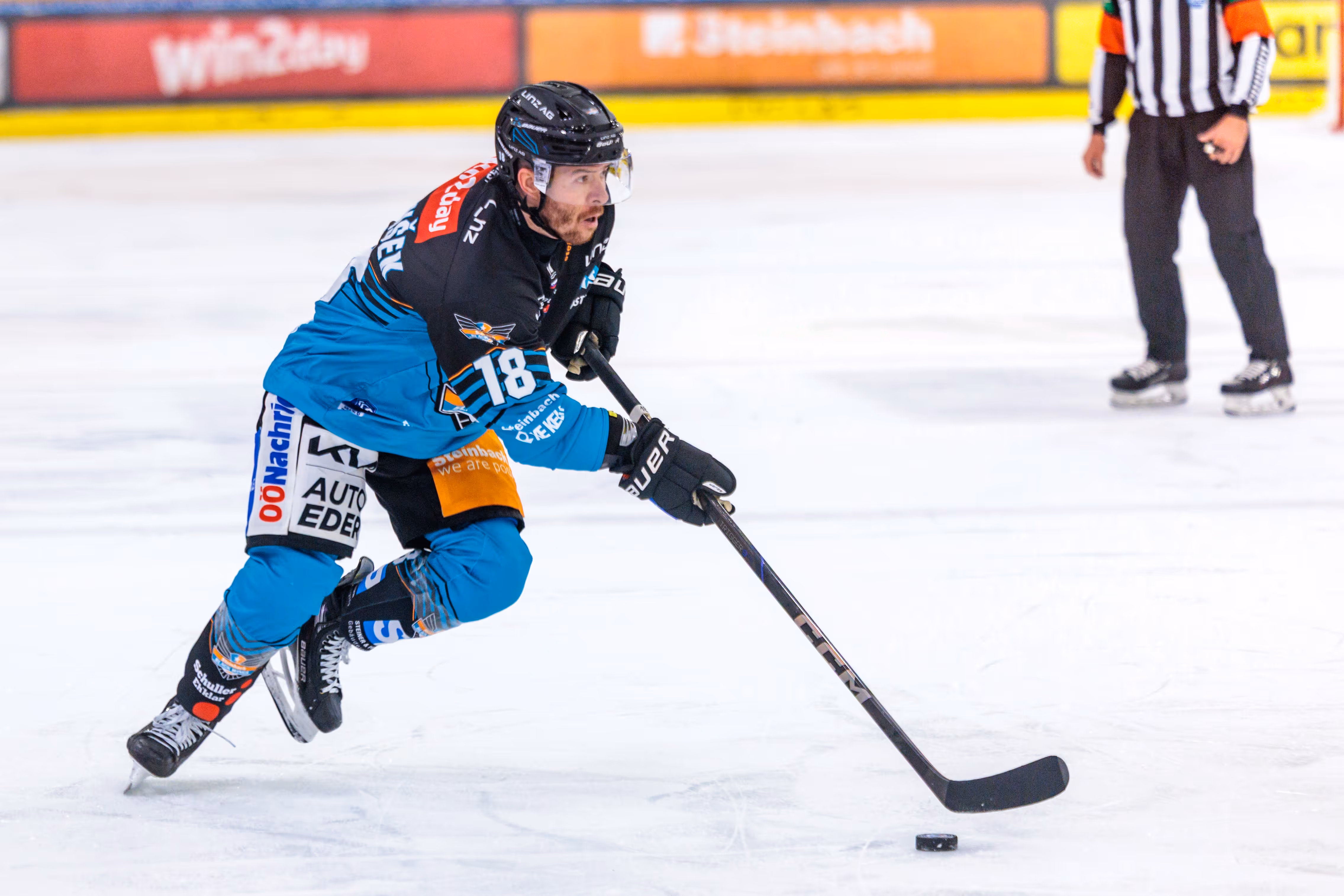 Der Eishockeyspieler Ken Ograjensek von den Black Wings Linz führt in voller Aktion den Puck mit seinem Schläger über das Eis