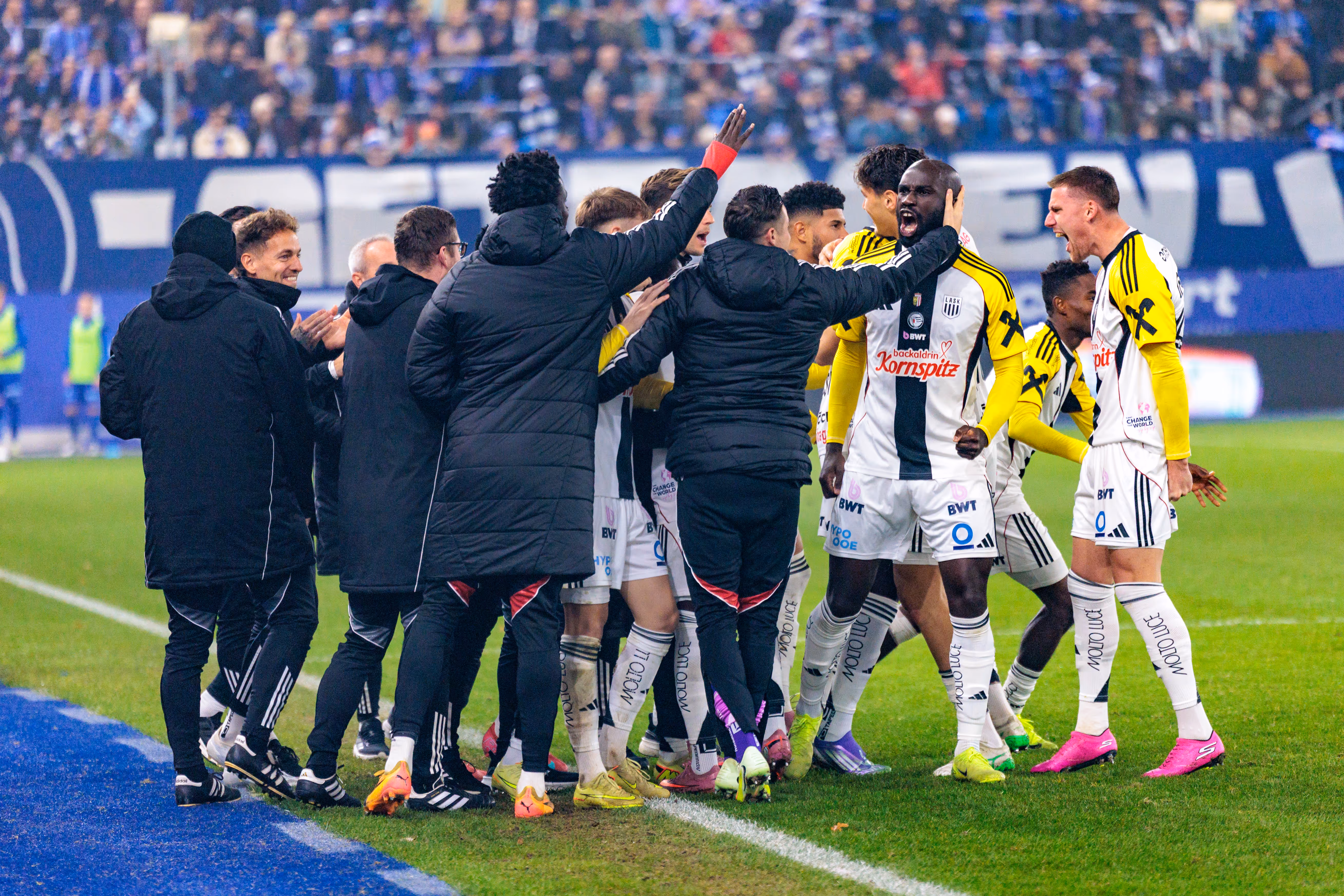 Die Spieler und Betreuer des LASK feiern in einer emotionalen Jubeltraube den entscheidenden Treffer von Torschütze Moses Adeniran im Linzer Derby