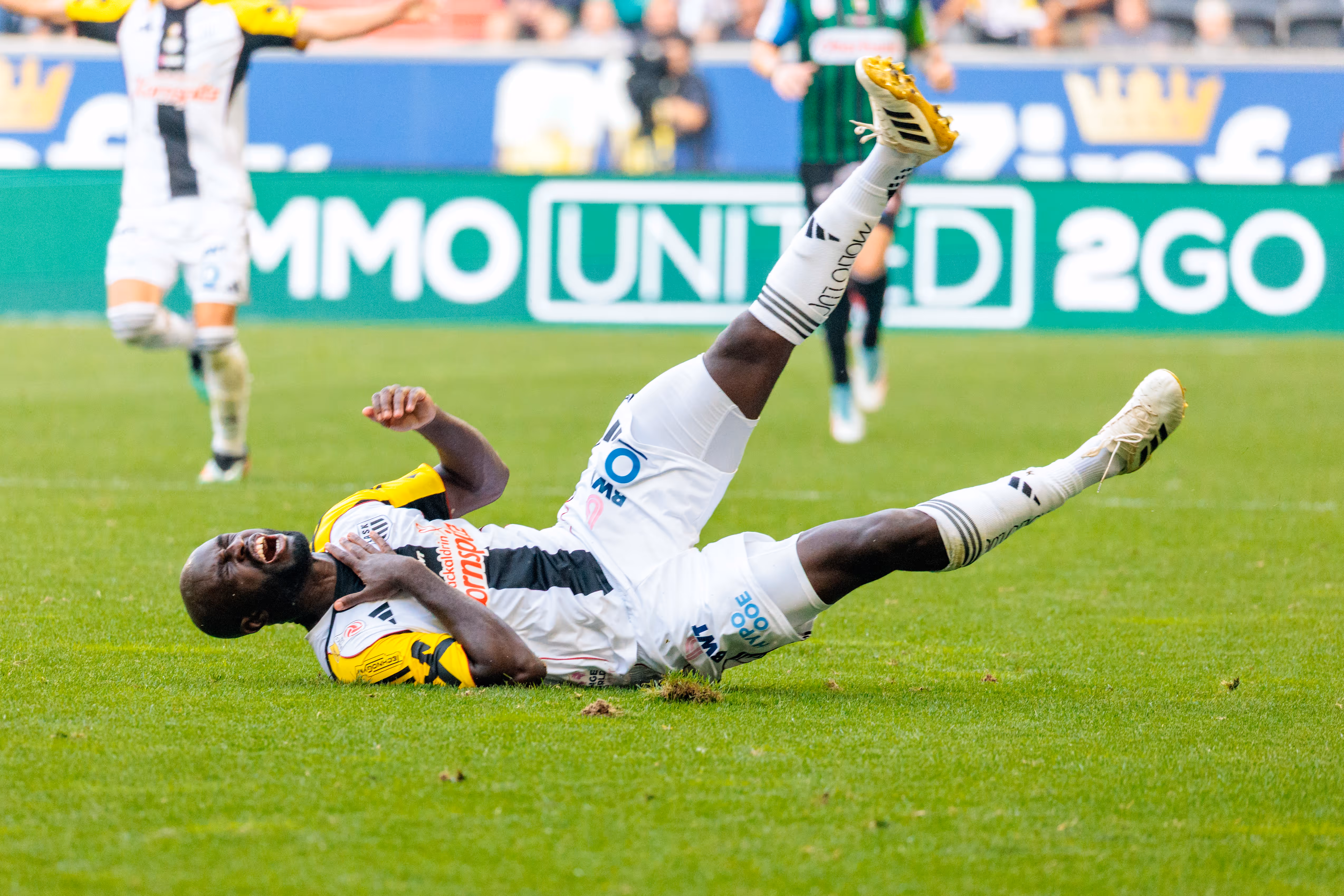Ein LASK-Spieler in seinem weiß-schwarzen Trikot liegt mit schmerzverzerrtem Gesicht auf dem Rasen während eines Bundesliga-Spiels gegen SV Ried