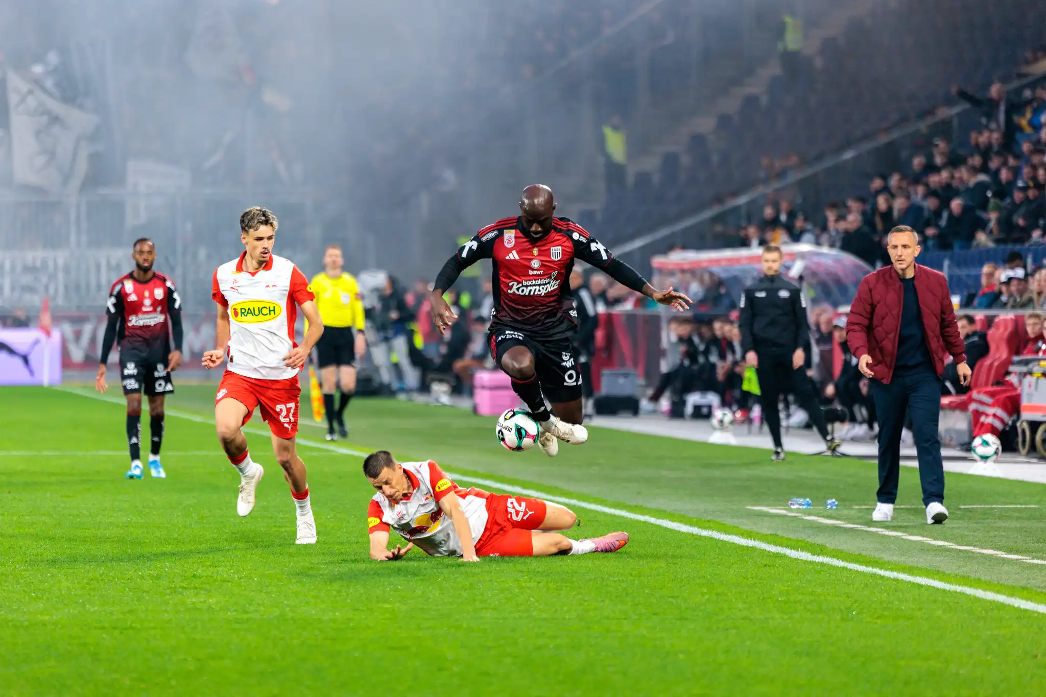 Ein Spieler des LASK setzt in der ADMIRAL Bundesliga zu einem spektakulären Sprung über einen am Boden liegenden Kontrahenten von Red Bull Salzburg an