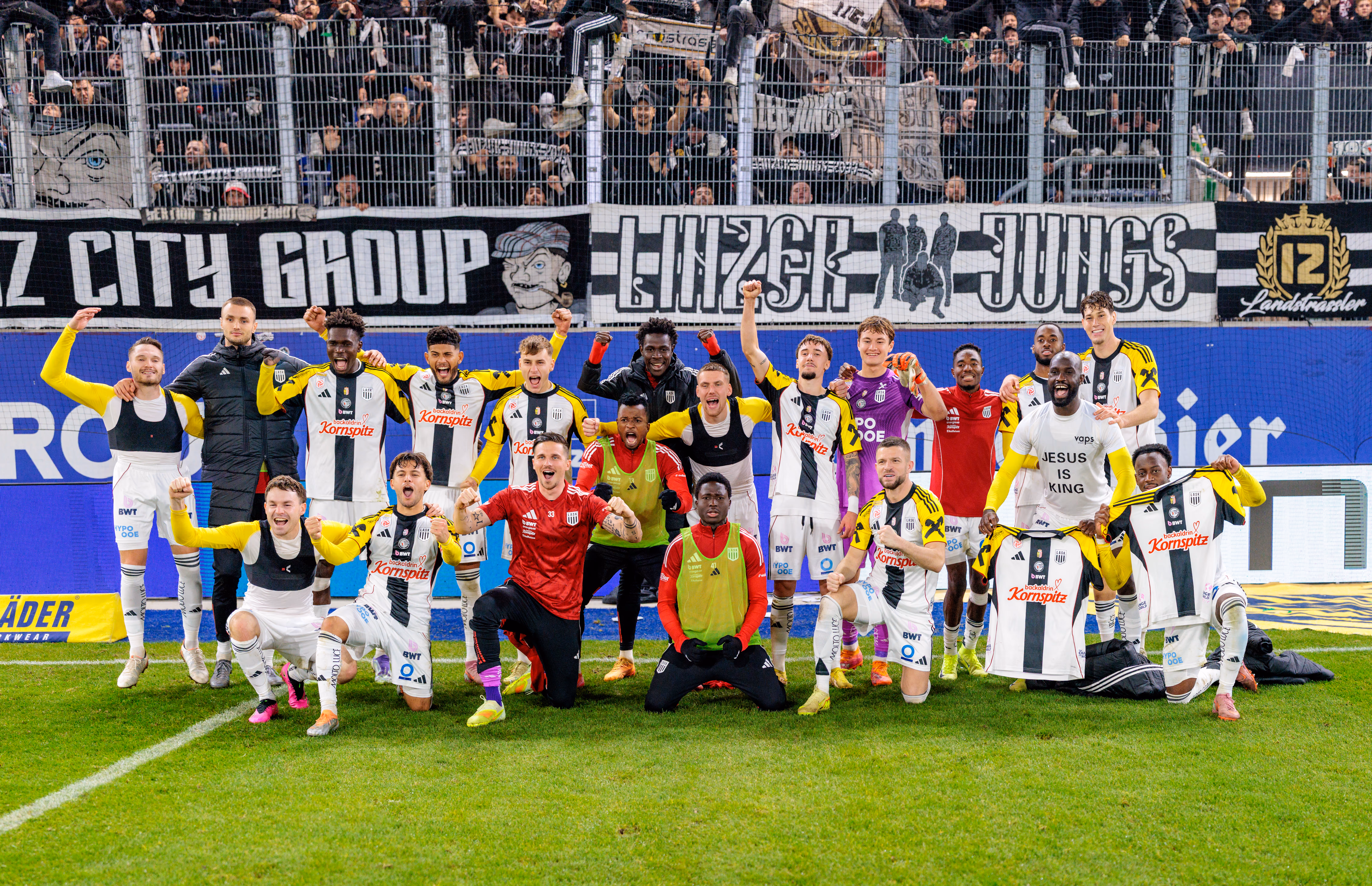 Die Fußballer des LASK feiern ausgelassen den Sieg im Linzer Derby und posieren für ein Mannschaftsfoto vor der jubelnden Fankurve