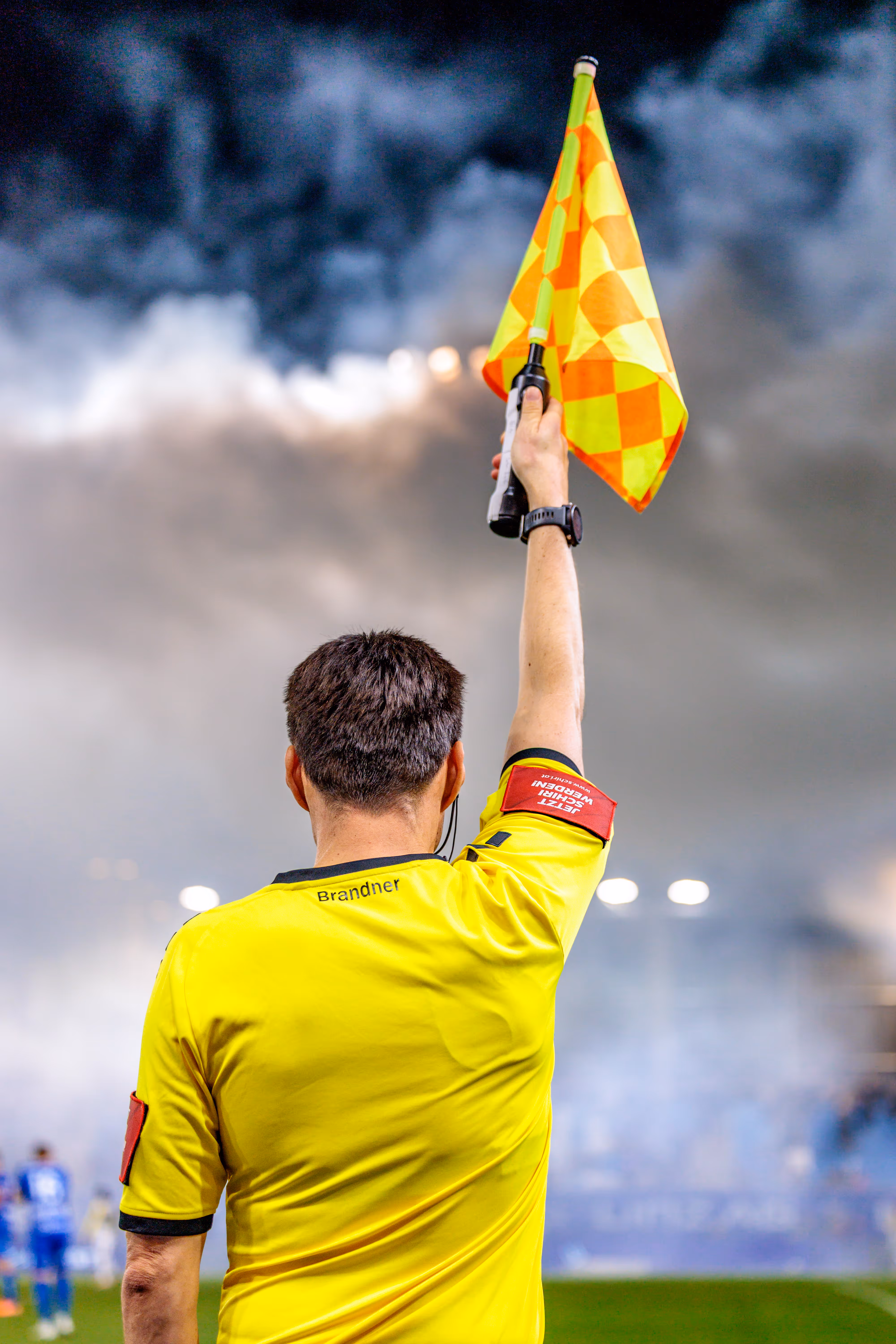 Ein Linienrichter hält während einer Spielunterbrechung aufgrund von starkem Rauch aus dem Fanblock seine Fahne senkrecht in die Luft