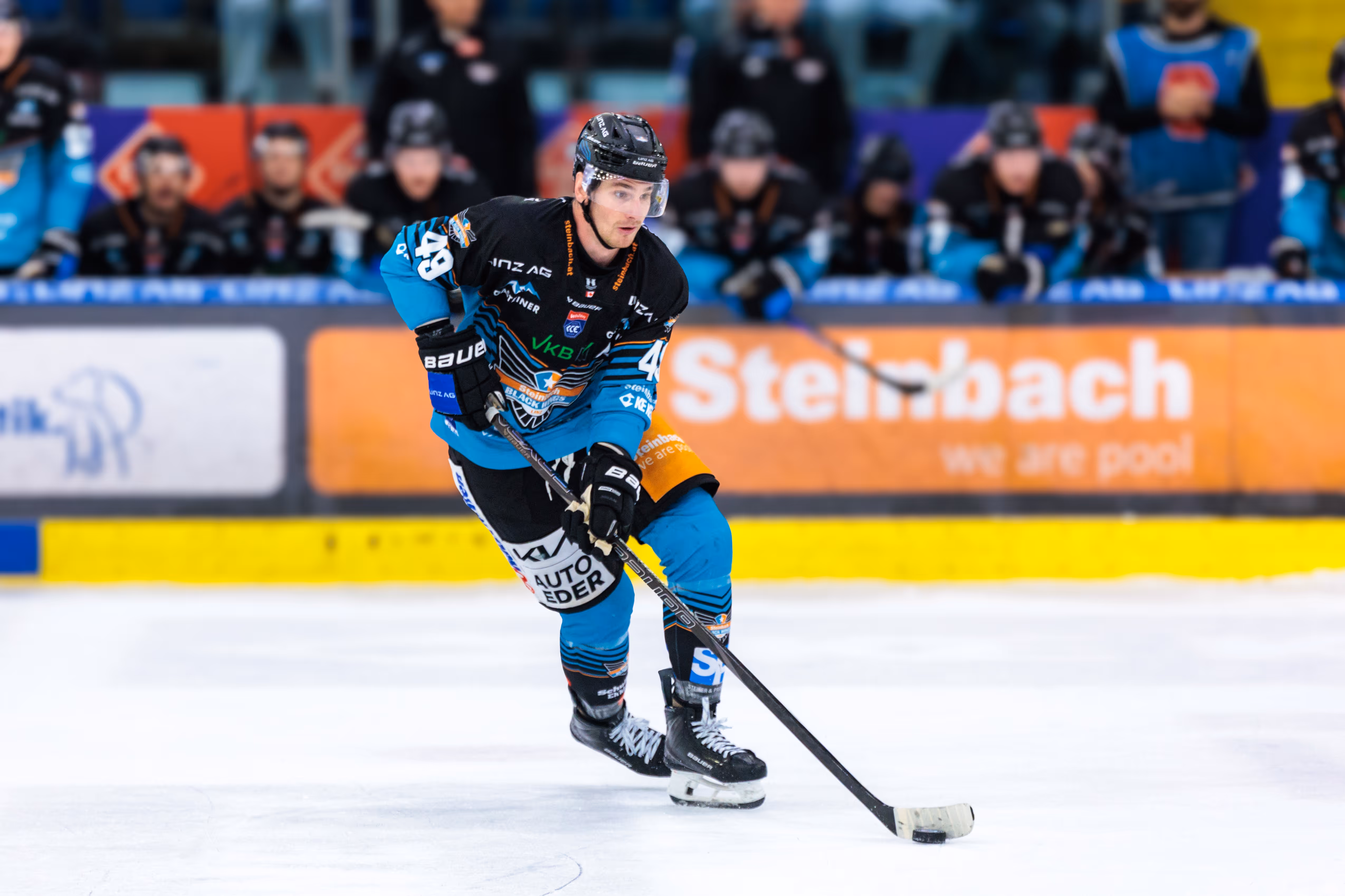 Der Eishockeyspieler Graham Knott von den Steinbach Black Wings Linz führt den Puck während eines Spiels konzentriert über das Eis