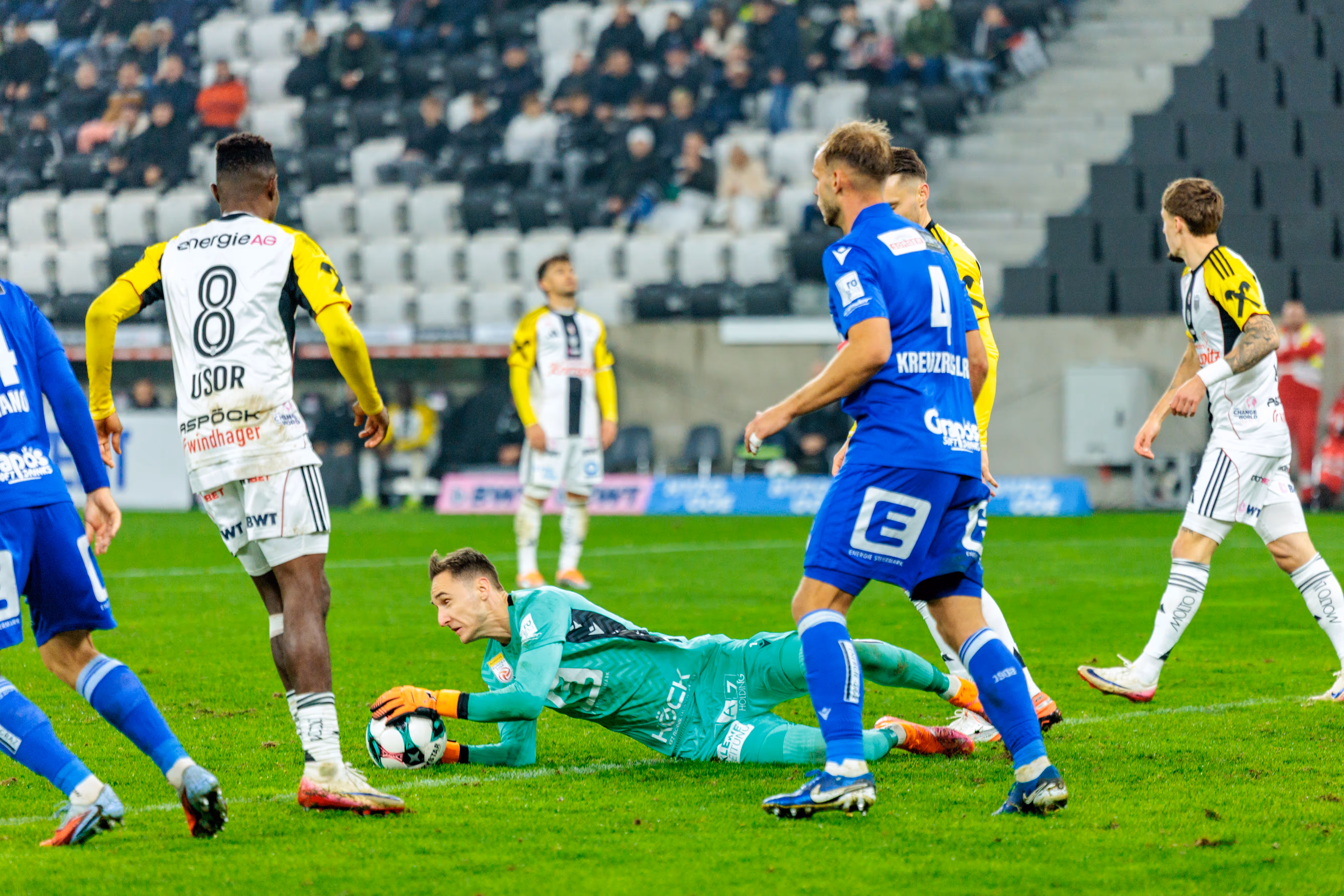 GAK-Goalie Jakob Meierhofer pariert den Ball am Boden liegend im Duell mit LASK-Stürmer Moses Usor