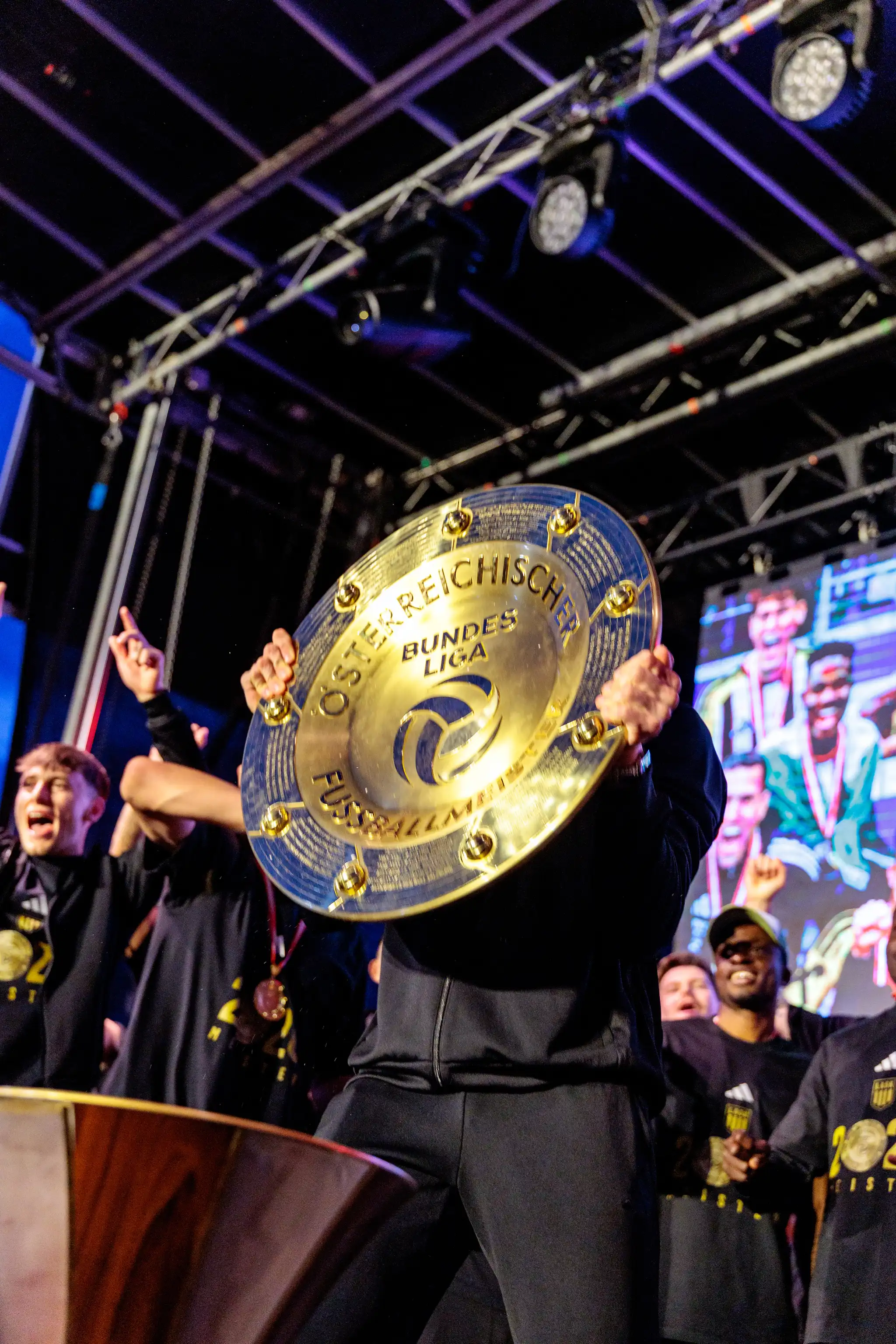 Ein Spieler hält den goldenen Meisterteller der österreichischen Bundesliga während der LASK-Meisterfeier direkt vor sein Gesicht