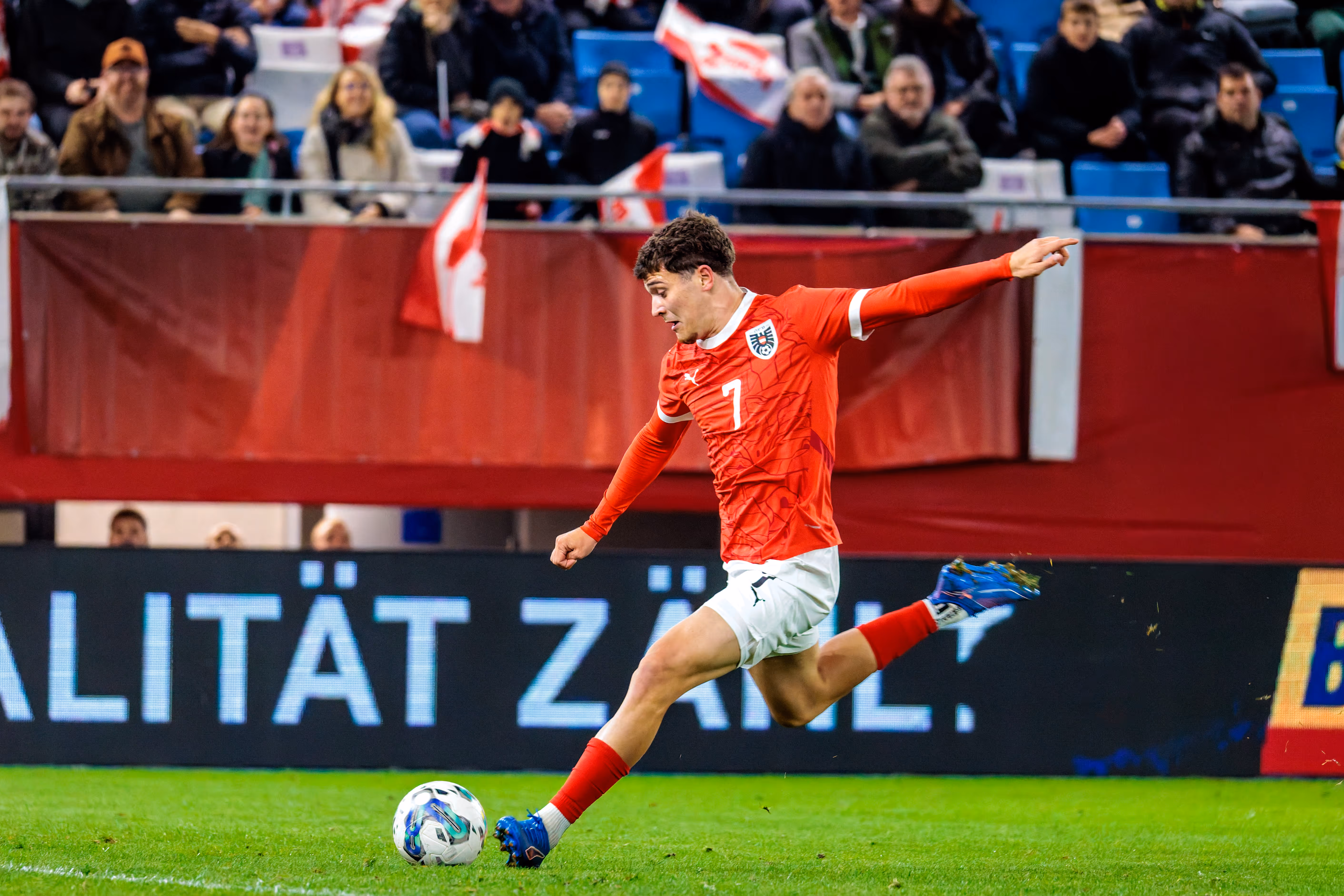 Der österreichische U21-Nationalspieler Moritz Wels schlägt in seinem roten Trikot mit der Nummer 7 eine Flanke mit dem rechten Fuß
