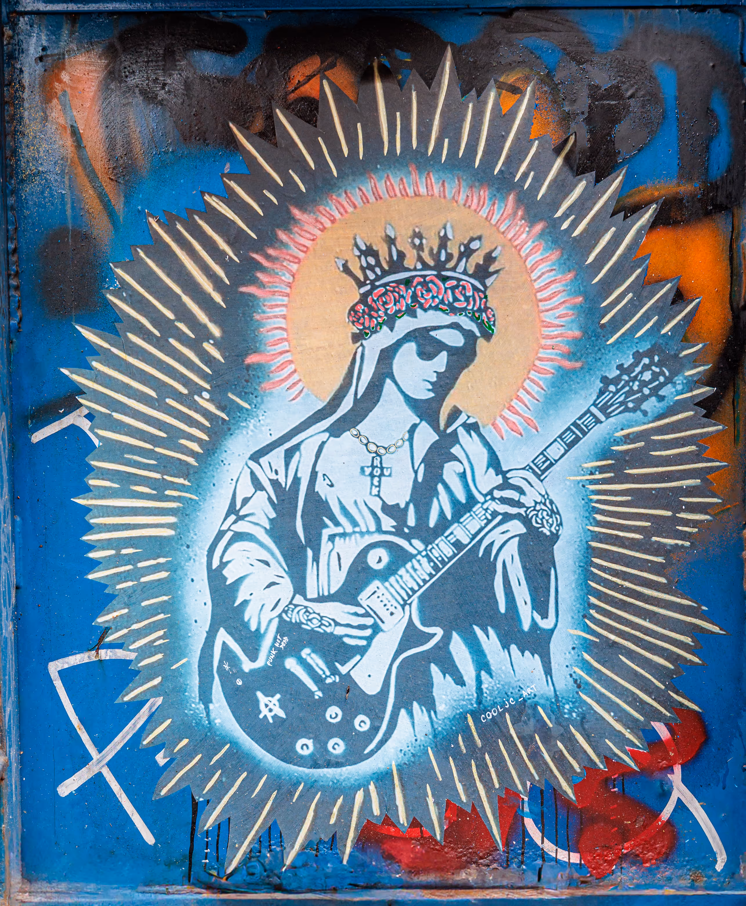 Ein rebellisches Wandgemälde in Amsterdam zeigt eine gekrönte Madonna mit E-Gitarre, umgeben von einem leuchtenden Strahlenkranz auf einer blauen Wand - 2025/06/10