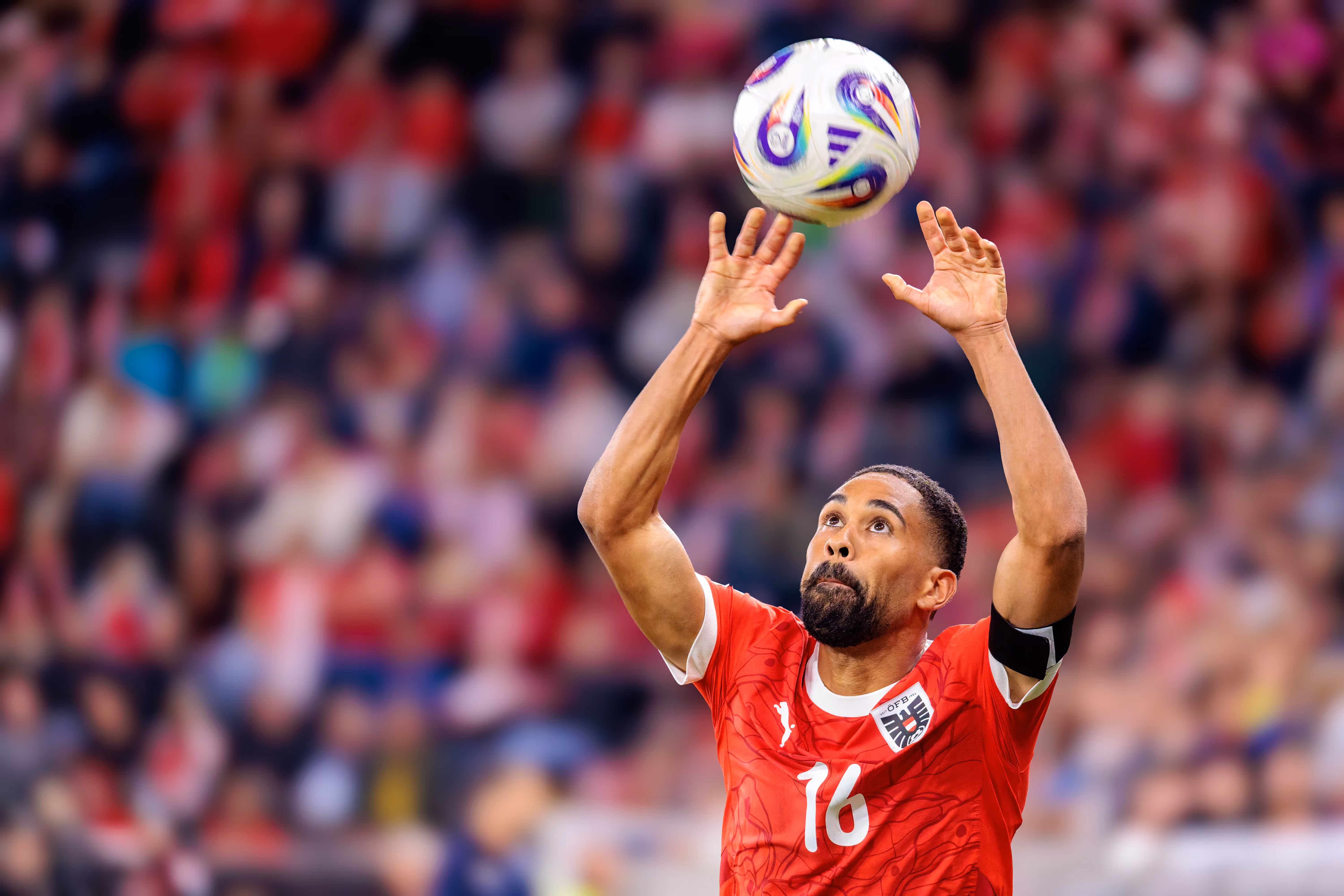 Der österreichische Fußballspieler Phillipp Mwene (Trikotnummer 16) blickt beim Ausführen eines Einwurfs konzentriert dem Fußball nach