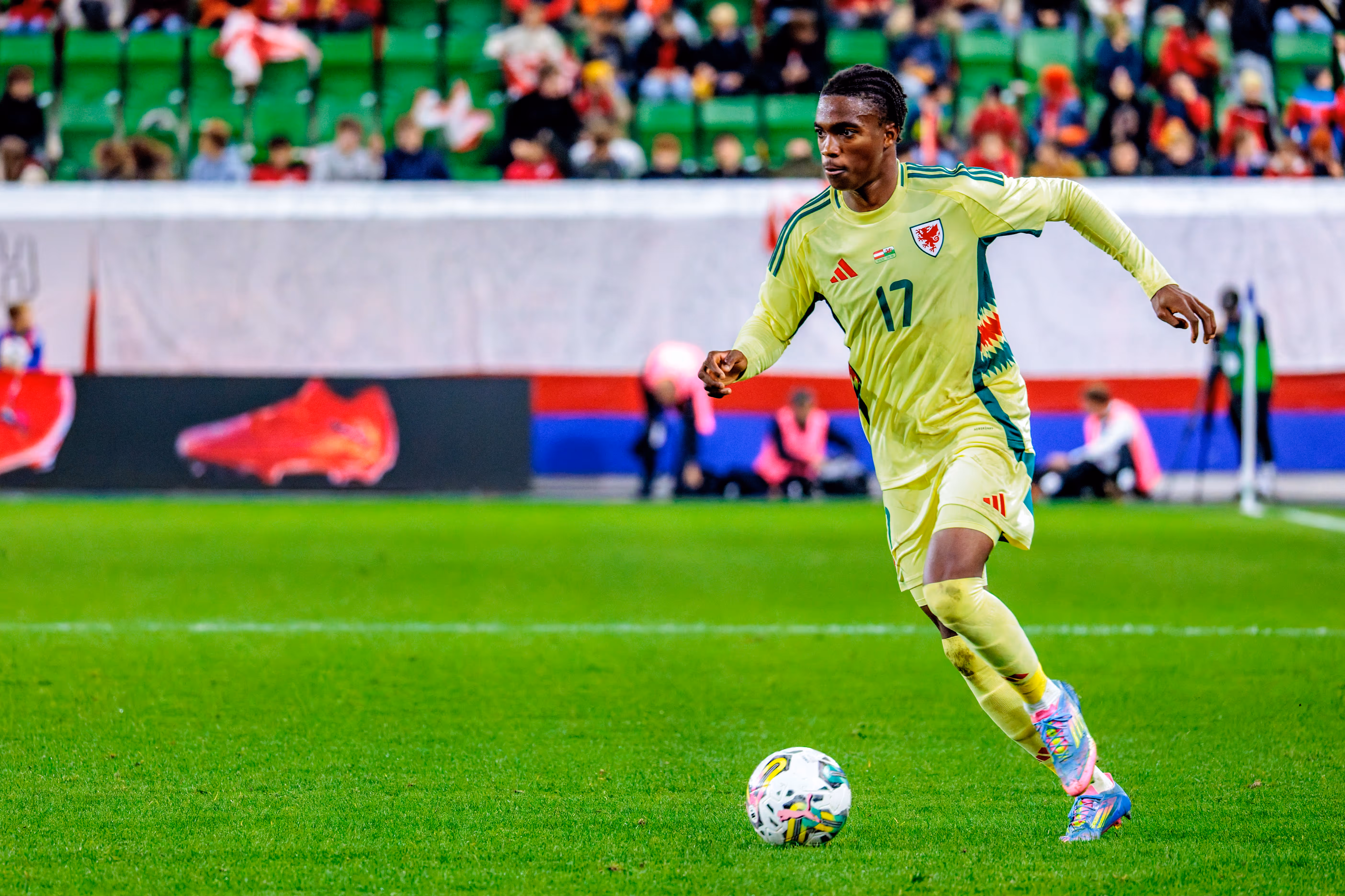 Der walisische U21-Nationalspieler Tanatswa Nyakuhwa dribbelt in seinem gelben Trikot mit der Nummer 17 konzentriert mit dem Ball