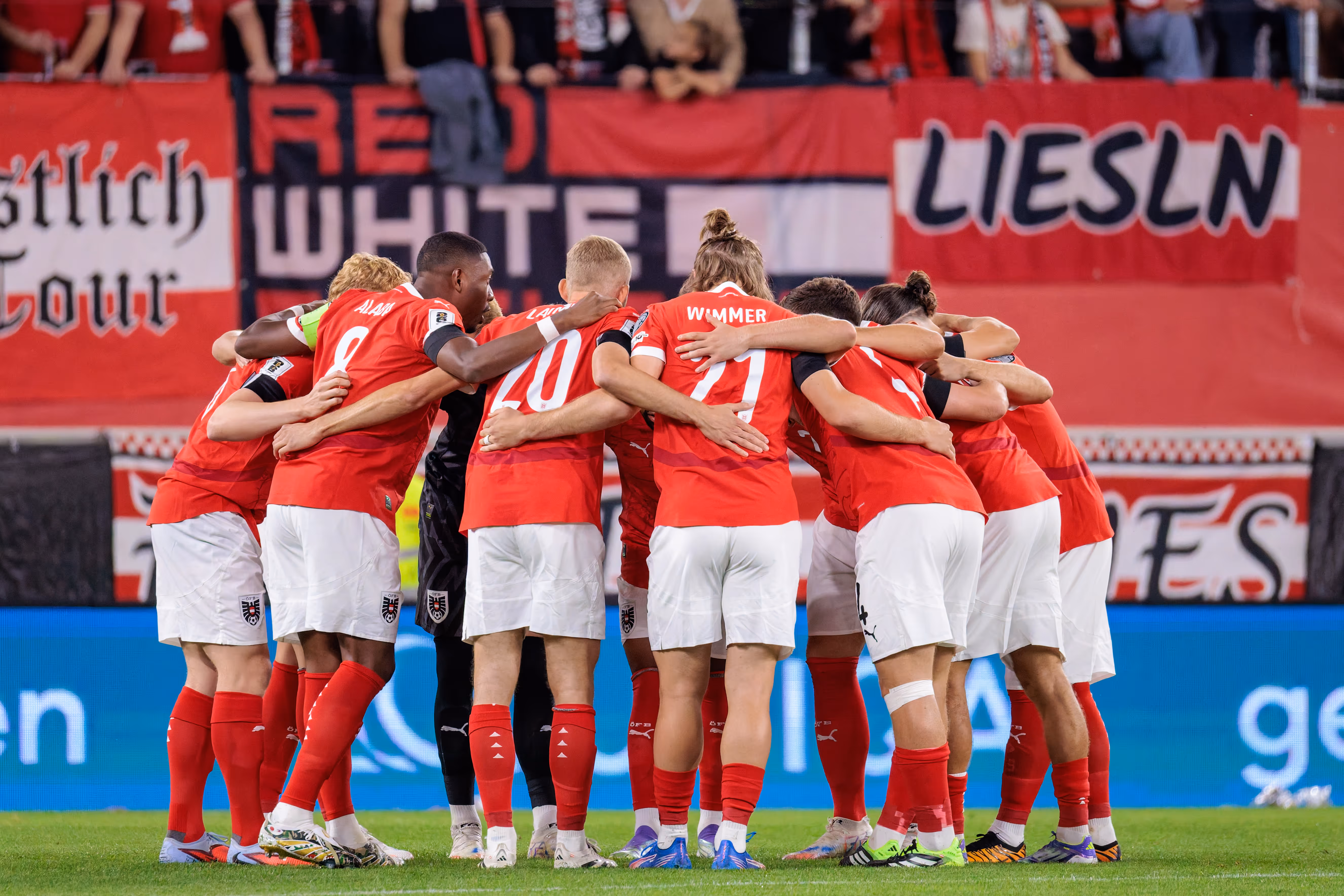 Spieler der österreichischen Nationalmannschaft wie Alaba, Laimer und Wimmer stehen in roten Trikots und weißen Hosen eng zusammen und bilden einen Teamkreis
