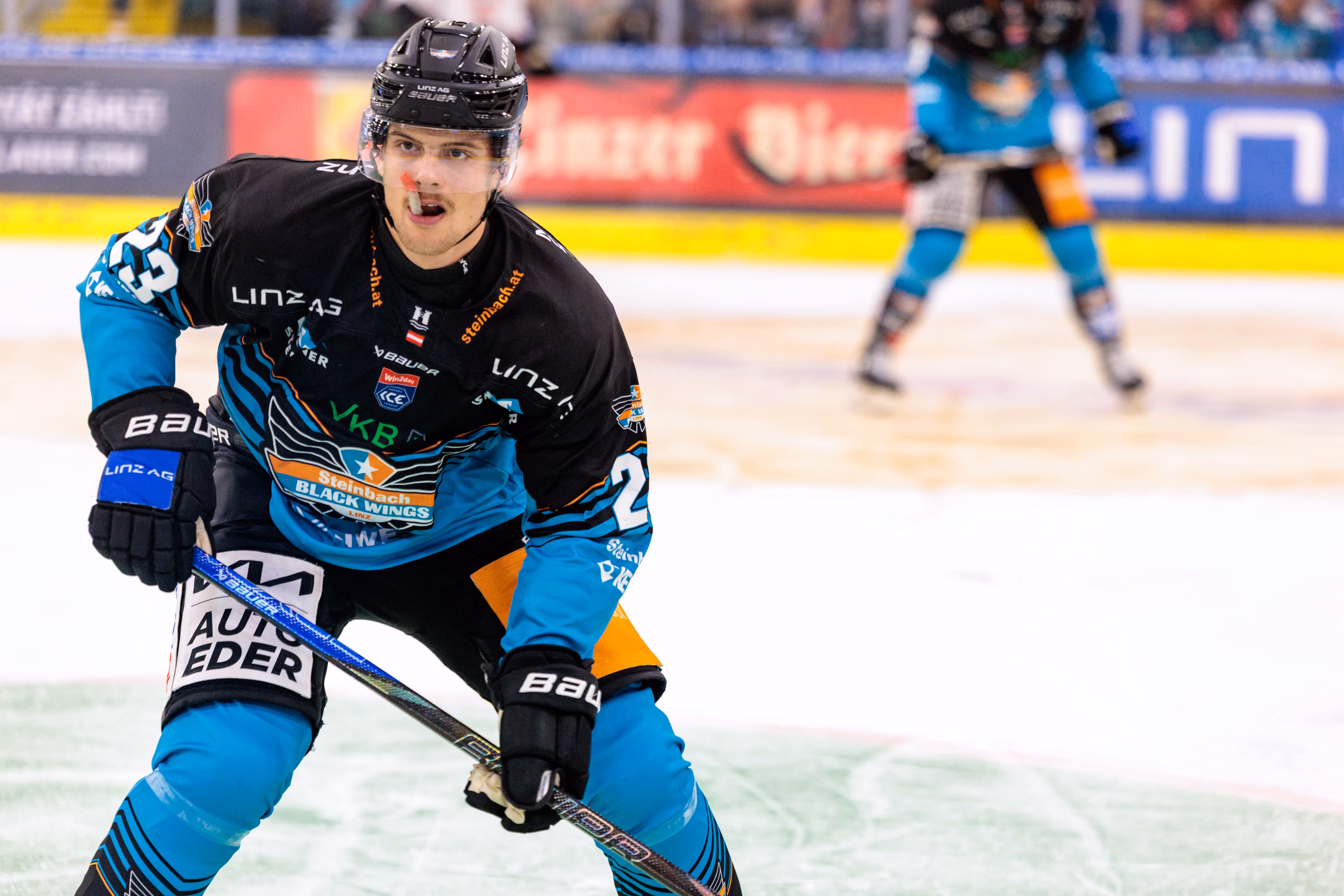 Eishockeyspieler Travis Barron der Steinbach Black Wings Linz mit der Nummer 25 in seinem schwarz-türkisen Trikot kaut auf seinem Mundschutz