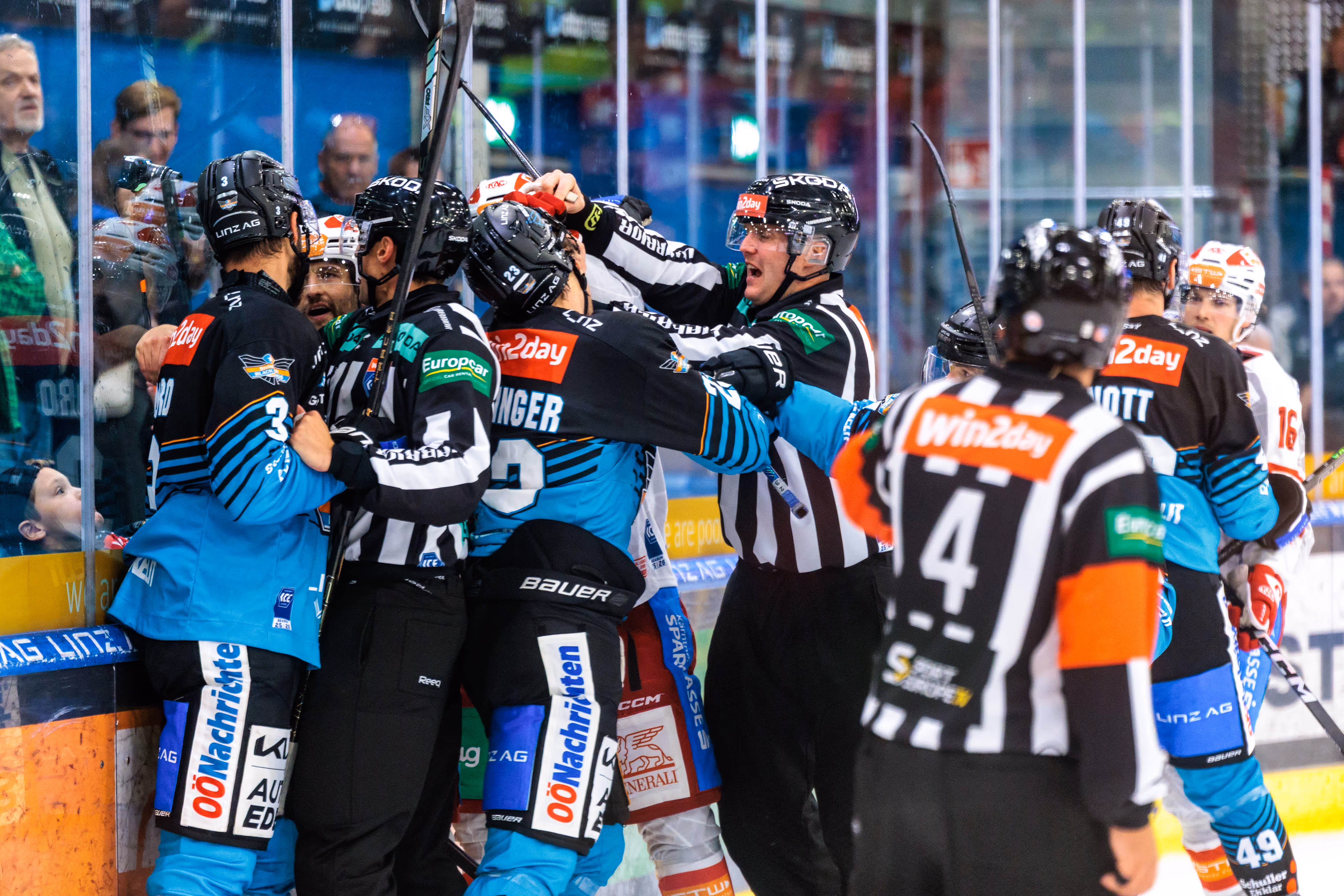 Eine heftige Rauferei zwischen den Eishockeyspielern der Black Wings Linz und des EC-KAC vor der Bande, bei der ein Schiedsrichter eingreift, um die Spieler zu trennen