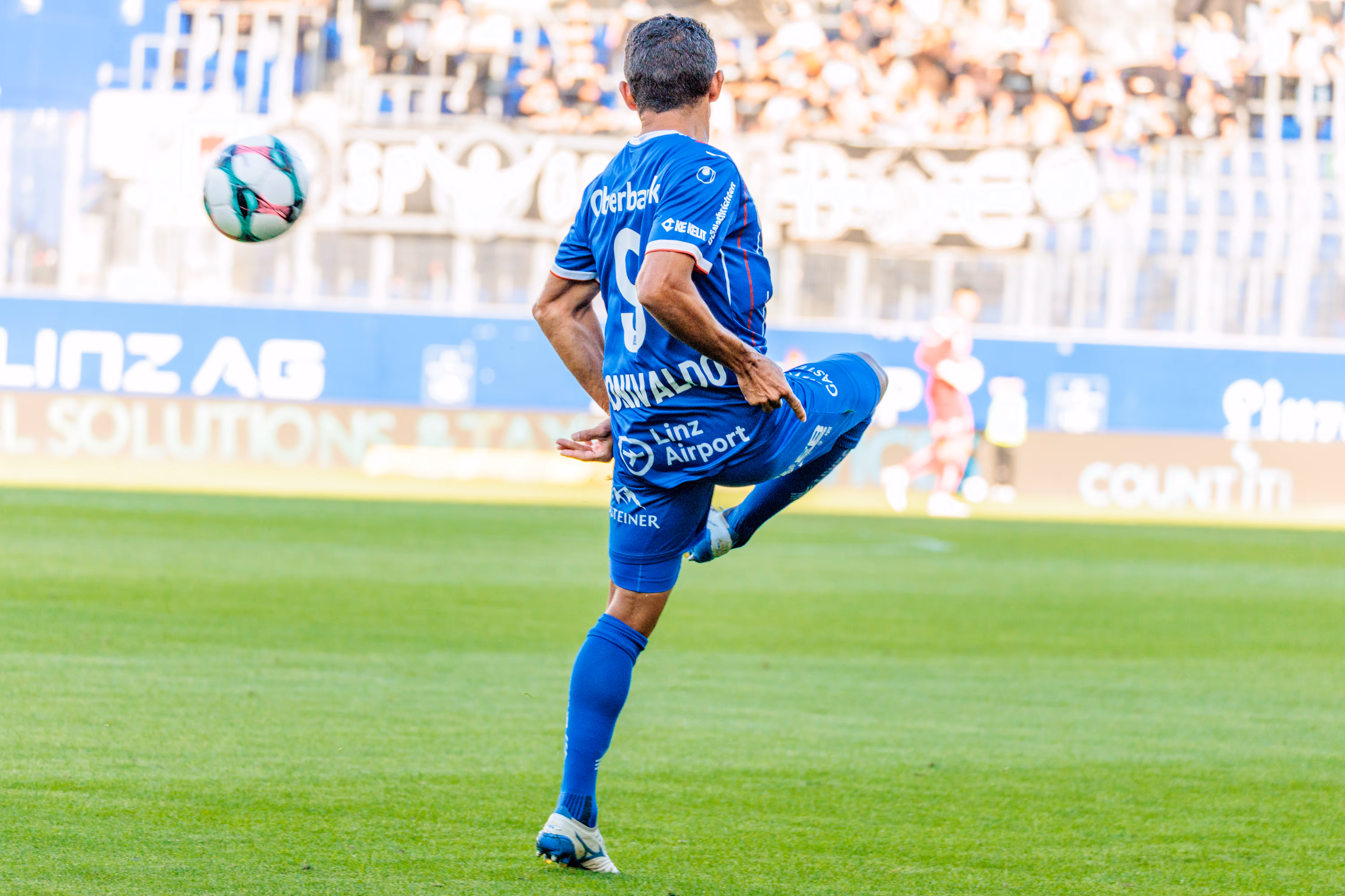 Rückansicht des Stürmers Ronivaldo vom FC Blau-Weiß Linz mit der Nummer 9, der während des Spiels elegant einen Ball in der Luft annimmt