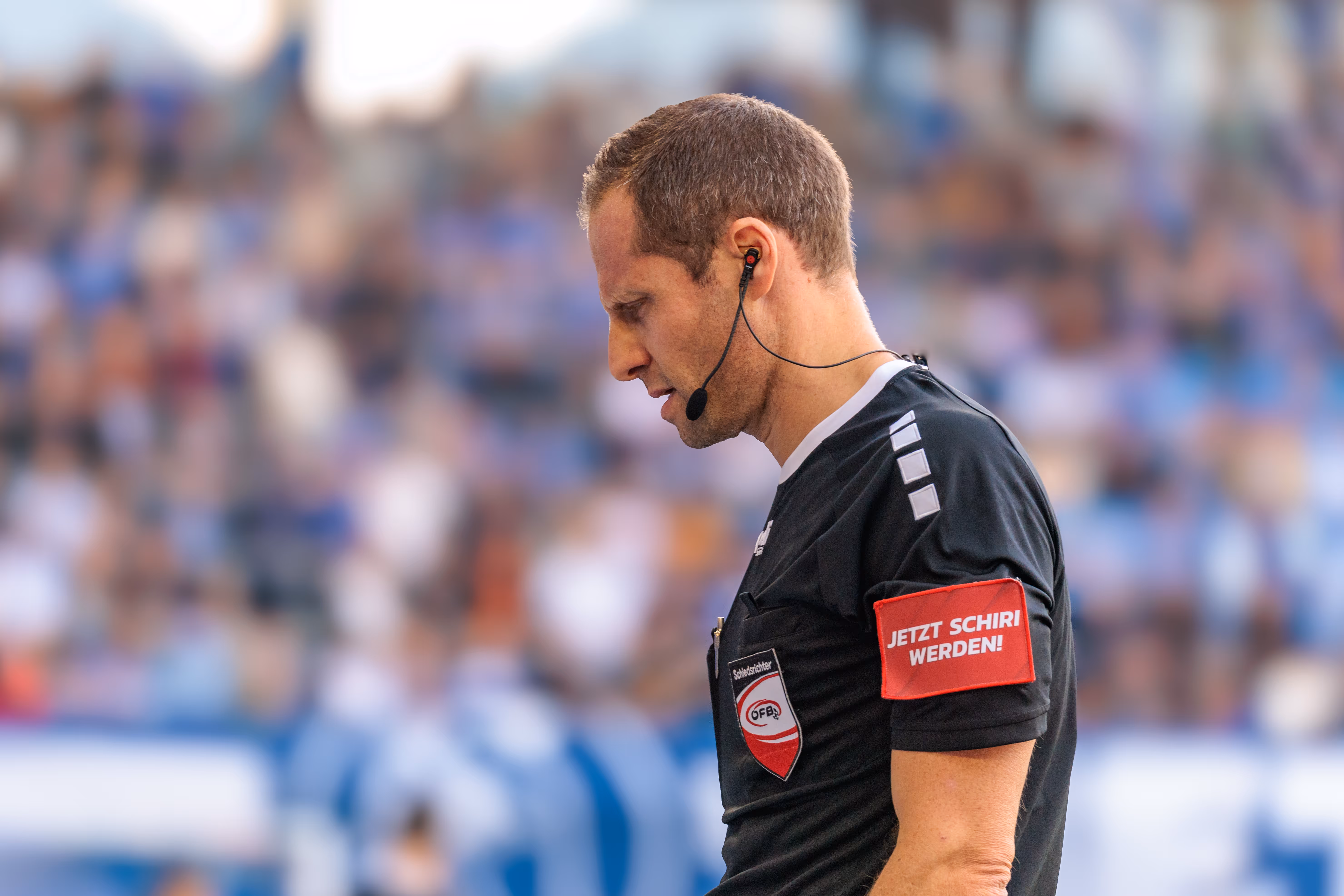 Ein Schiedsrichter blickt während eines Fußballspiels konzentriert auf den VAR Bildschirm