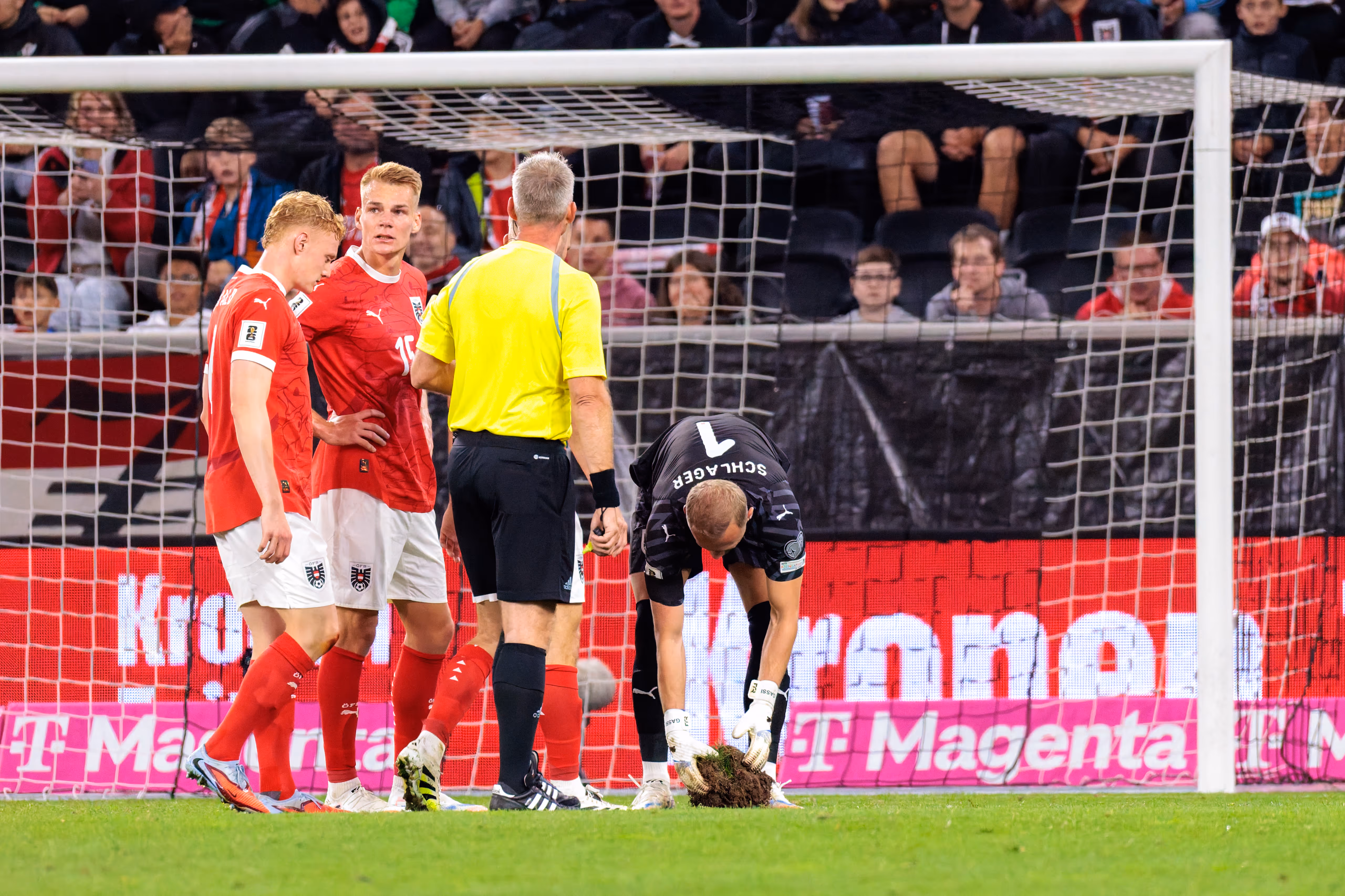 Österreichs Torwart Alexander Schlager (Nummer 1) inspiziert den Schaden am Rasen während des WM-Qualifikationsspiels gegen Zypern, beobachtet von vom Schiedsrichter und mehreren österreichischen Spielern