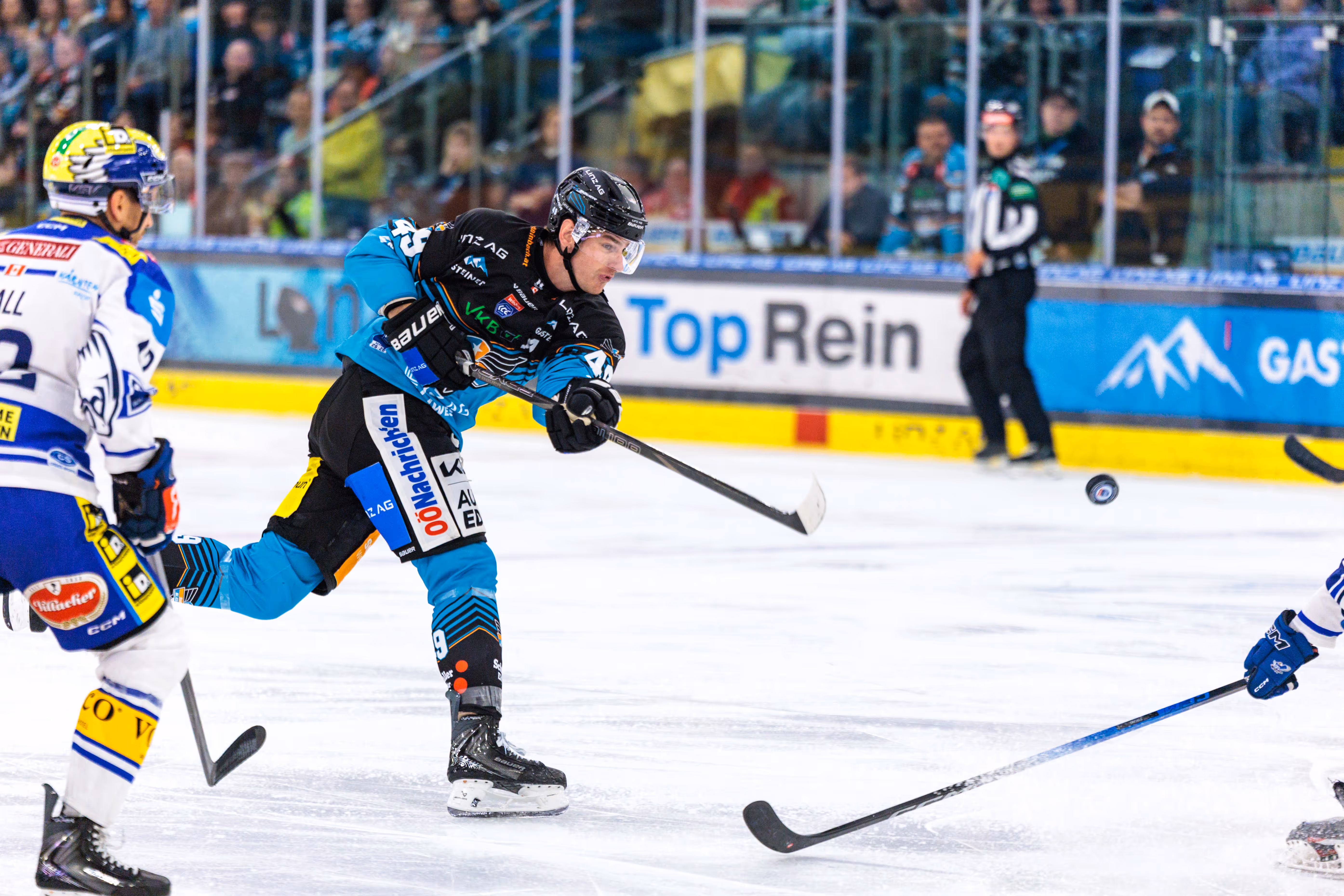 Eishockeyspieler Emilio Romig von den Steinbach Black Wings Linz schießt den Puck während eines Ice Hockey League Spiels