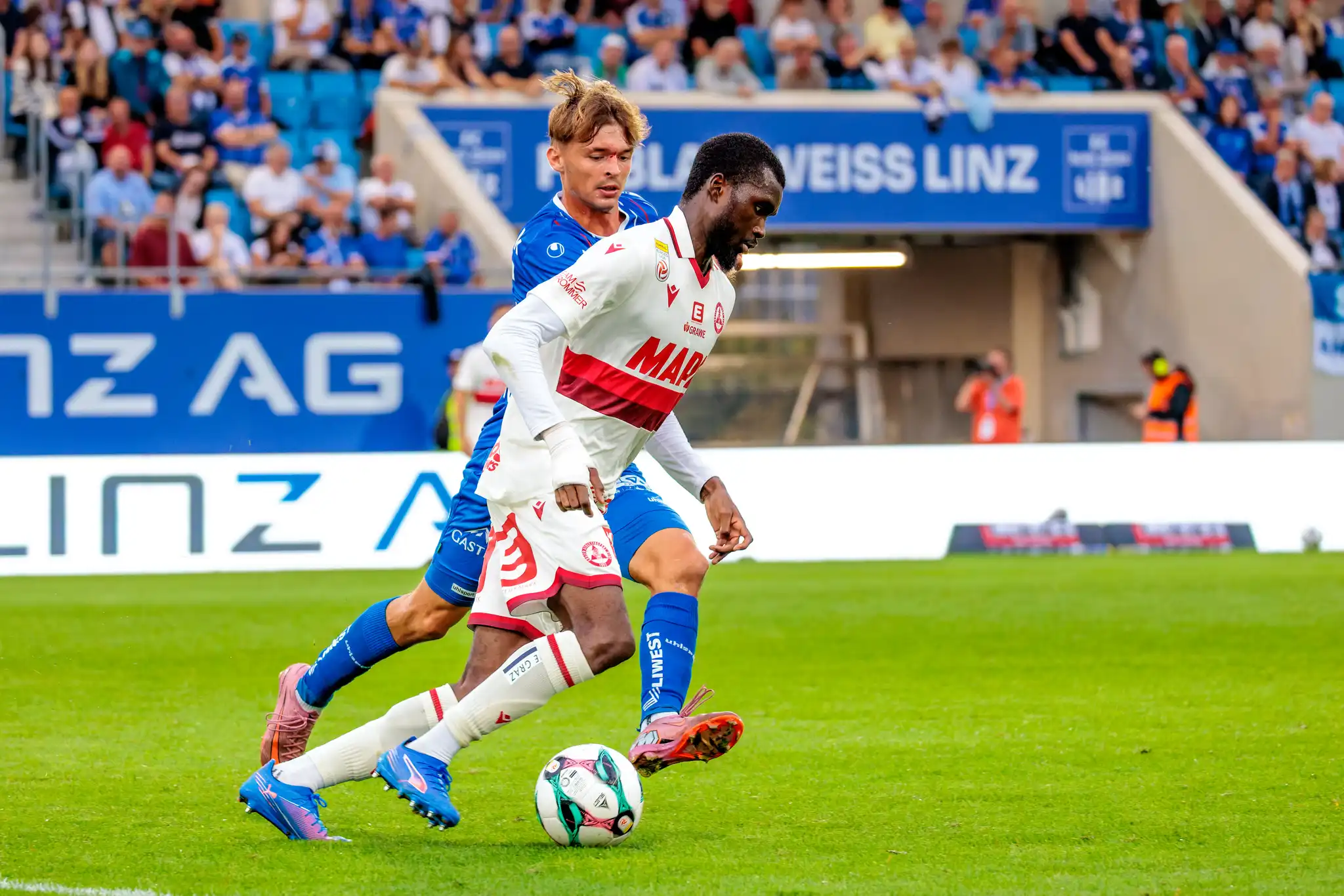 Sadik Fofana vom Grazer AK dribbelt am Ball, während Simon Seidl vom FC Blau-Weiß Linz versucht, ihm den Ball abzunehmen
