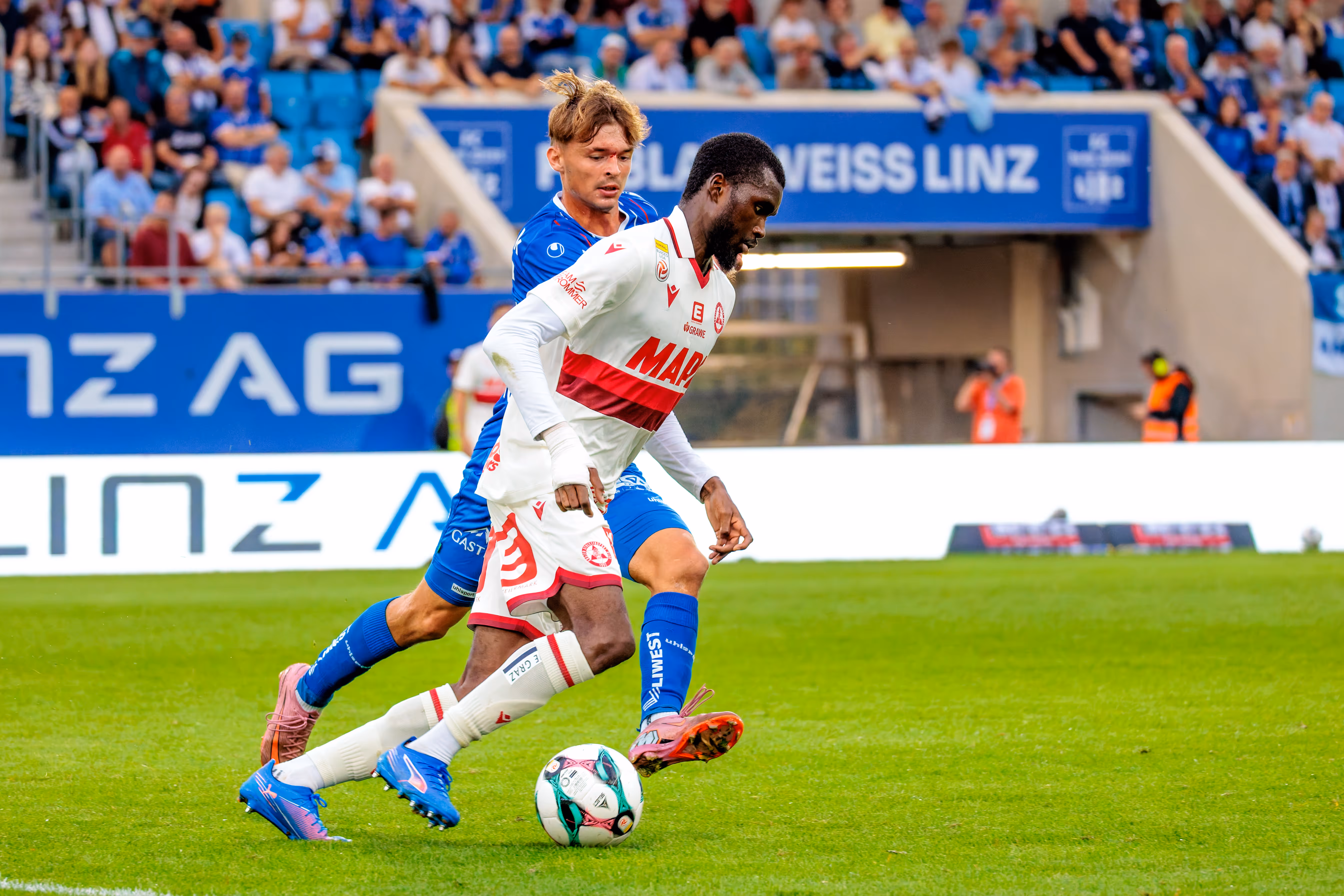 Sadik Fofana vom Grazer AK dribbelt am Ball, während Simon Seidl vom FC Blau-Weiß Linz versucht, ihm den Ball abzunehmen