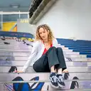 Eine junge Frau mit lockigem Haar sitzt auf einer Treppe mit farbenfrohem Pop-Art-Muster