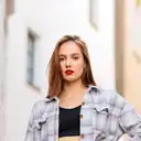 Junge Frau mit rotem Lippenstift und kariertem Hemd blickt vor hellem Hintergrund in die Kamera  lens: 56mm F1.4 DC DN | Contemporary 018