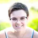 Nahaufnahme einer freundlich lächelnden jungen Frau mit kurzen Haaren und modischer Brille vor hellem, verschwommenem Hintergrund  lens: 56mm F1.4 DC DN | Contemporary 018