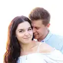 Nahaufnahme eines lächelnden jungen Paares, eng beieinander stehend, mit Lichtreflexen im Haar und einem stark überbelichteten Hintergrund  lens: 56mm F1.4 DC DN | Contemporary 018