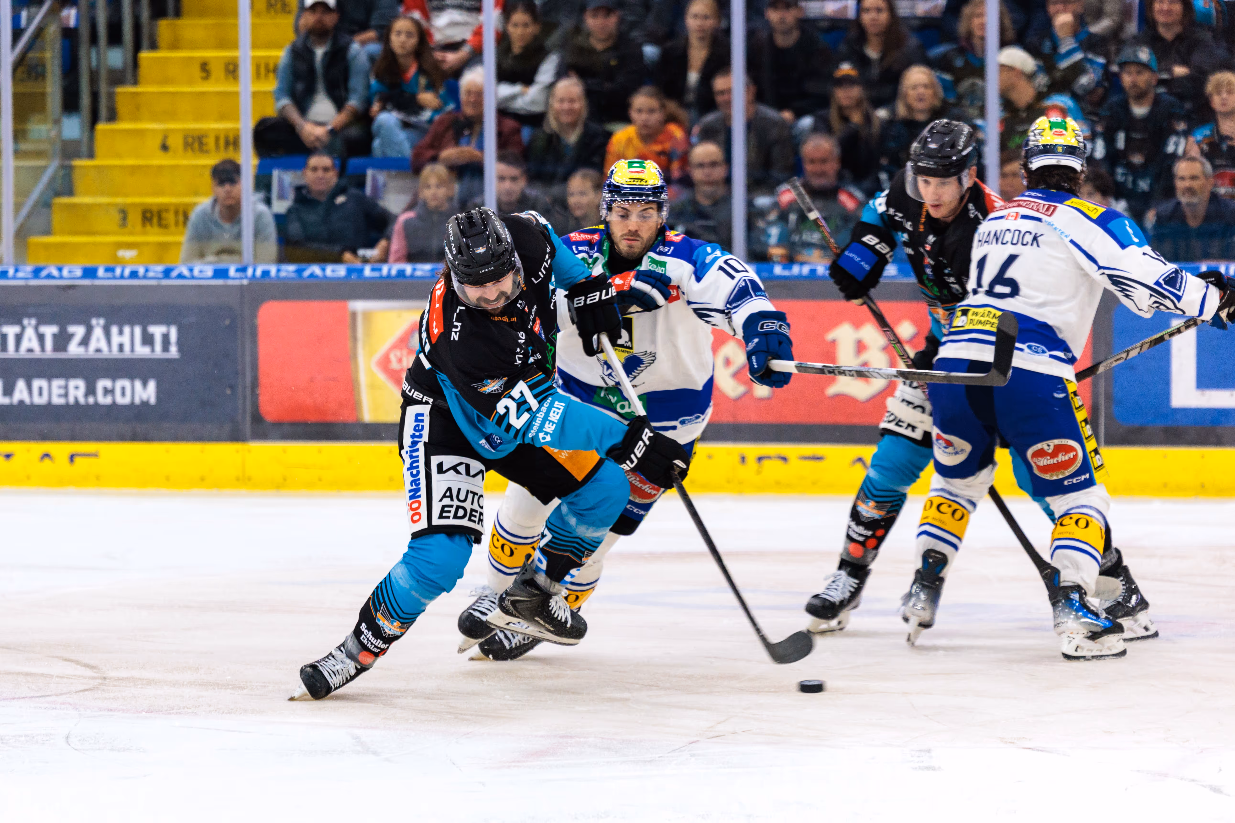 Eishockeyspieler Shawn St-Amant der Steinbach Black Wings Linz in dynamischer Puckführung gegen Kevin Hancock des EC VSV auf dem Eis