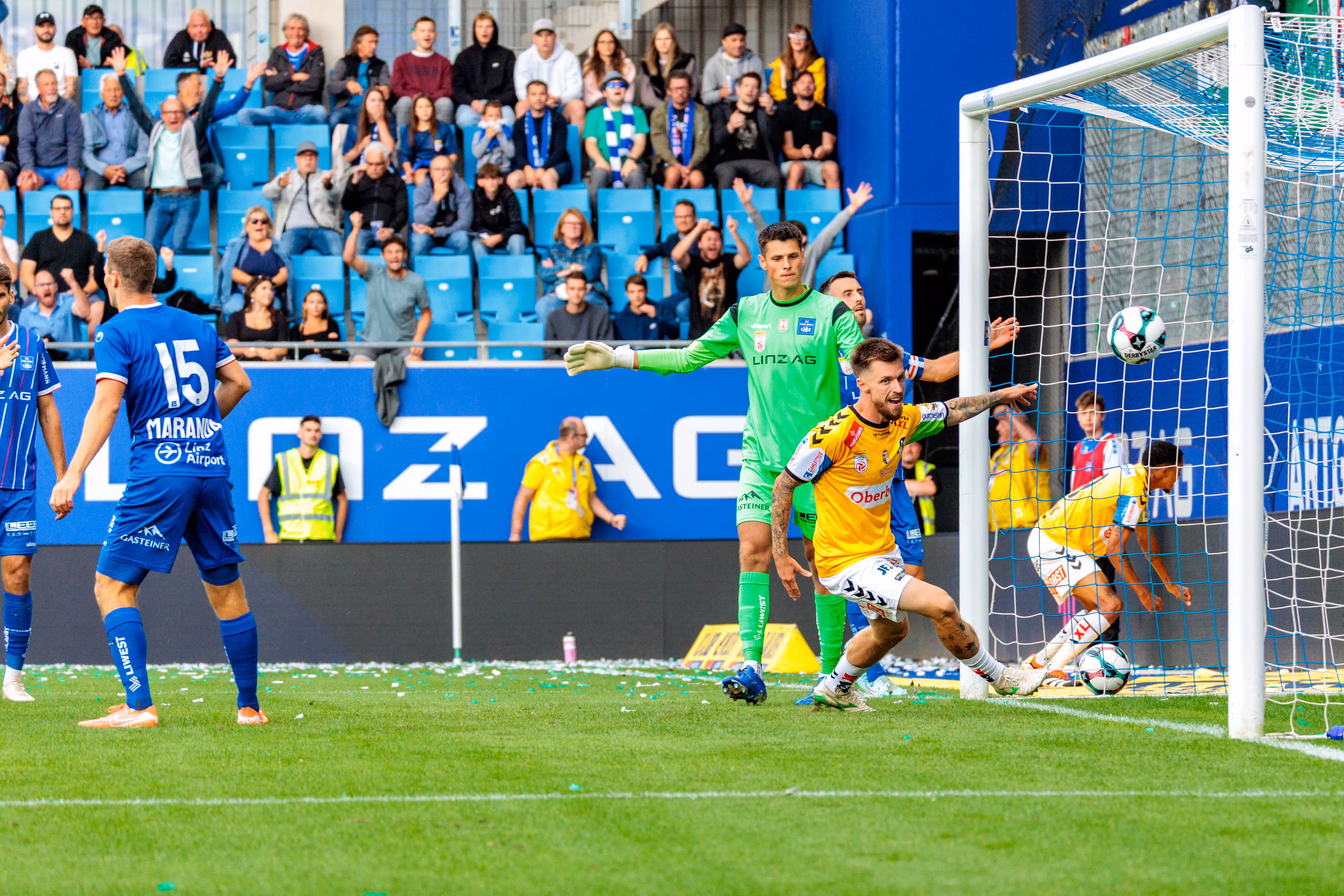 Der SV Ried Spieler Pomer jubelt ausgelassen über sein Tor zum 1:0 gegen Blau-Weiß Linz, der Ball ist im Netz und Fans feiern im Hintergrund