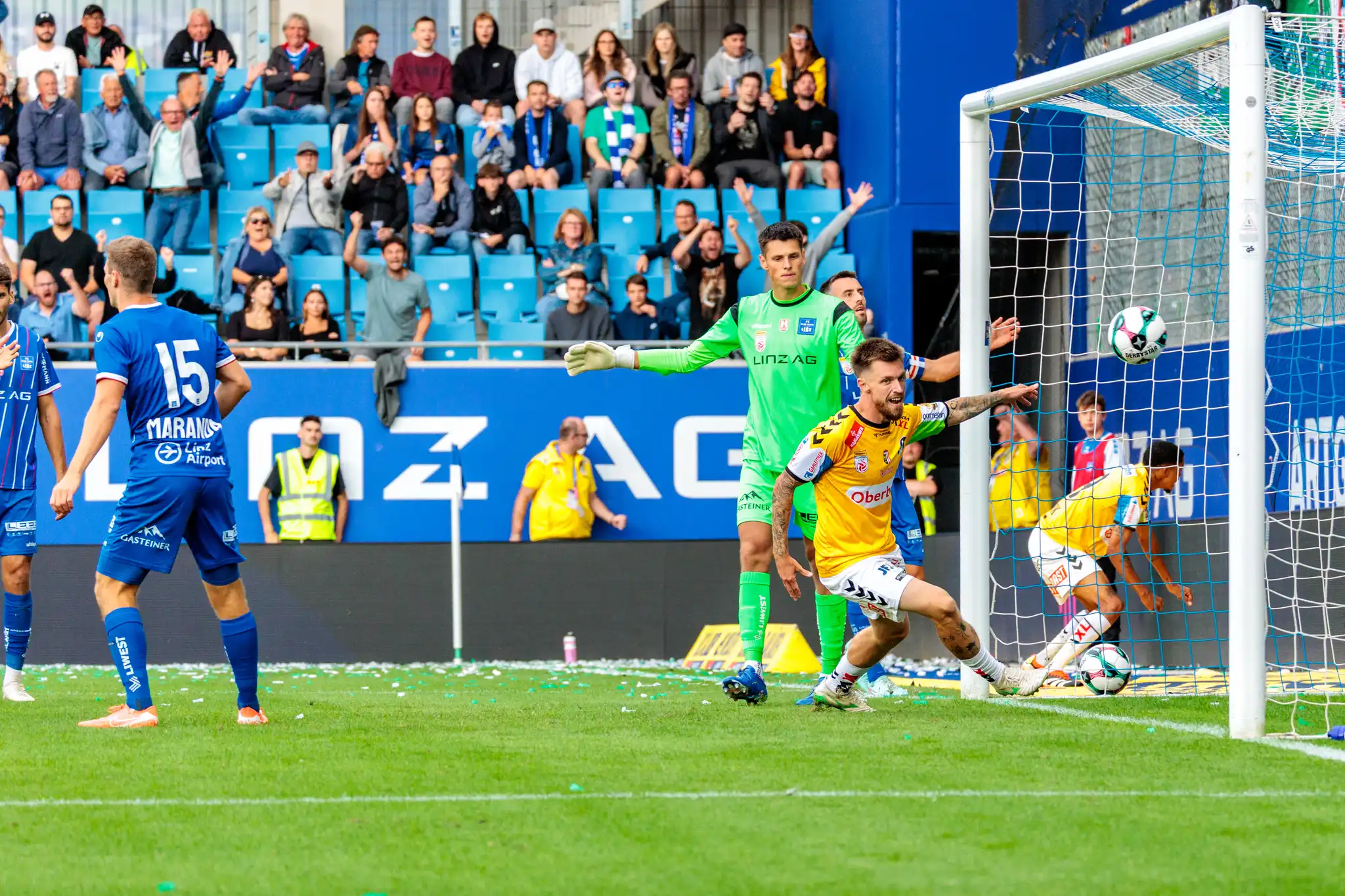 Der SV Ried Spieler Pomer jubelt ausgelassen über sein Tor zum 1:0 gegen Blau-Weiß Linz, der Ball ist im Netz und Fans feiern im Hintergrund
