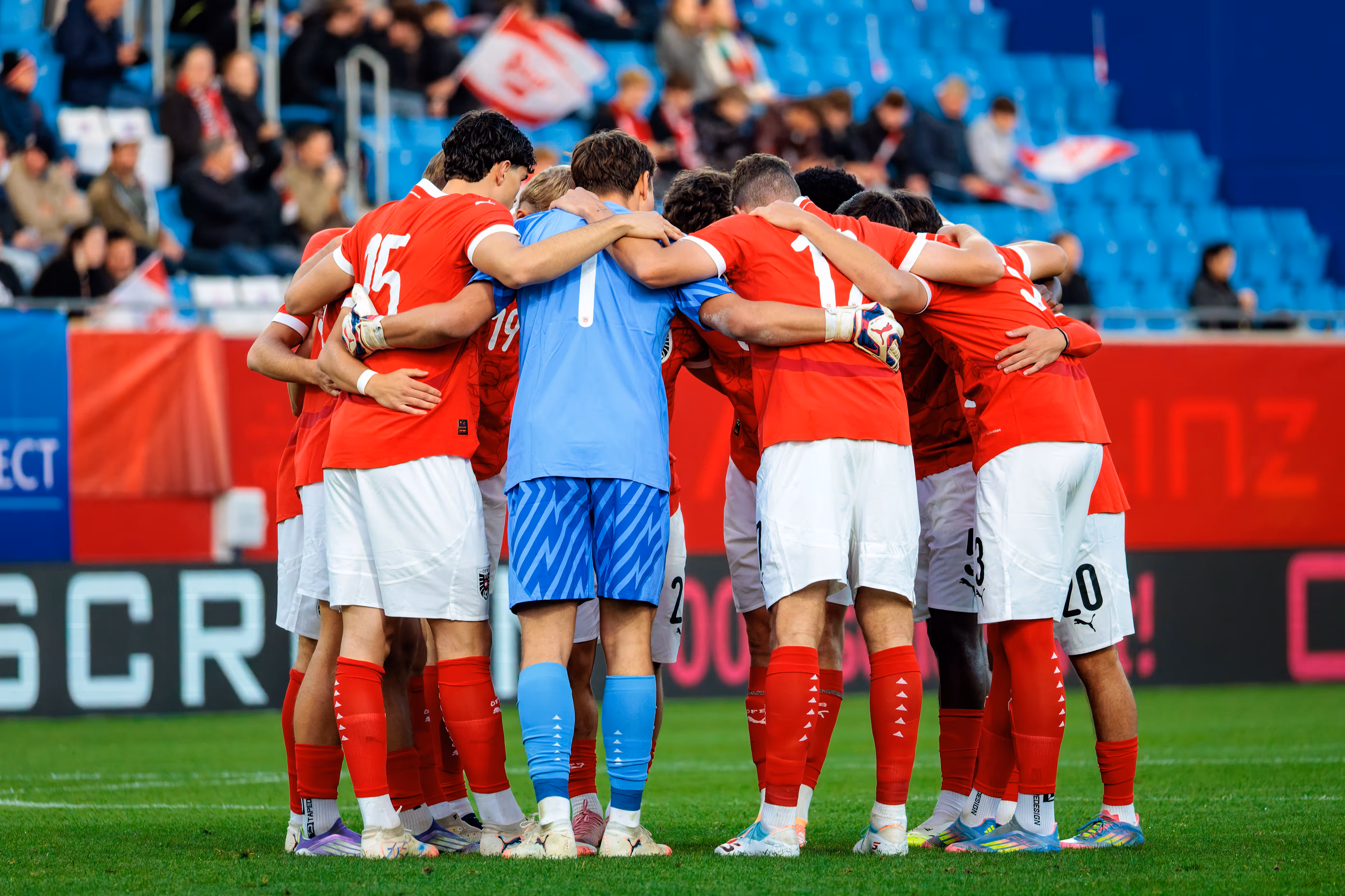 Die Spieler der österreichischen U21-Nationalmannschaft stehen von hinten gesehen in einem engen Kreis zusammen und umarmen sich beim Team-Huddle
